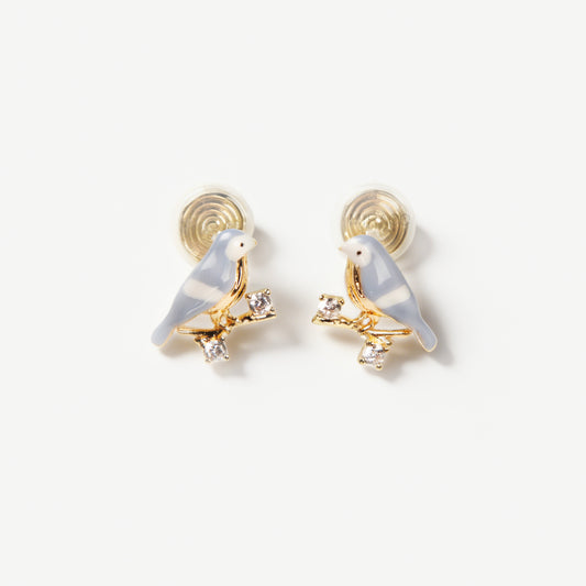 Pair of periwinkle blue enamel bird clip-on earrings perched on gold-tone branches with small crystals and invisible coil back closures.