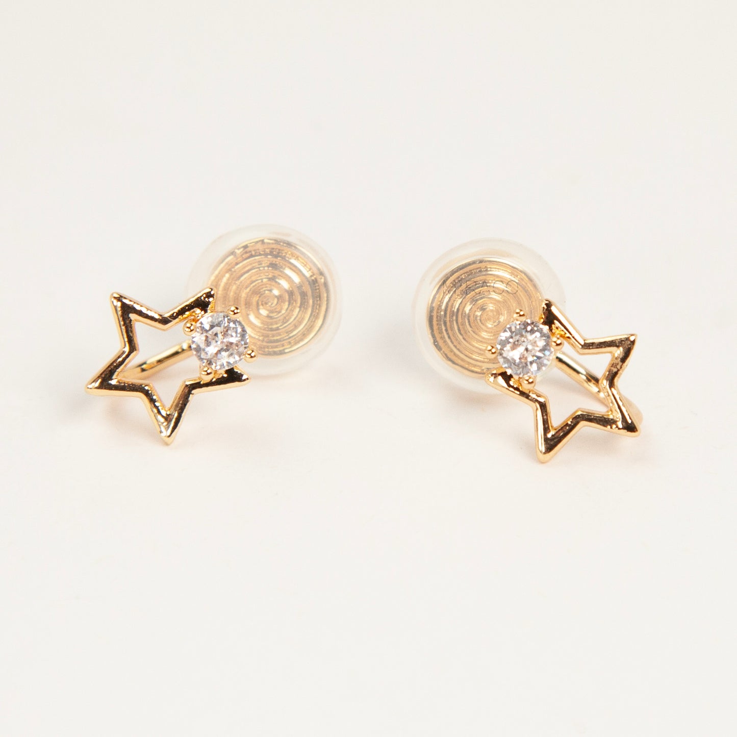 Pair of gold-tone open star-shaped clip-on earrings featuring a small clear crystal and comfortable invisible coil back closures.