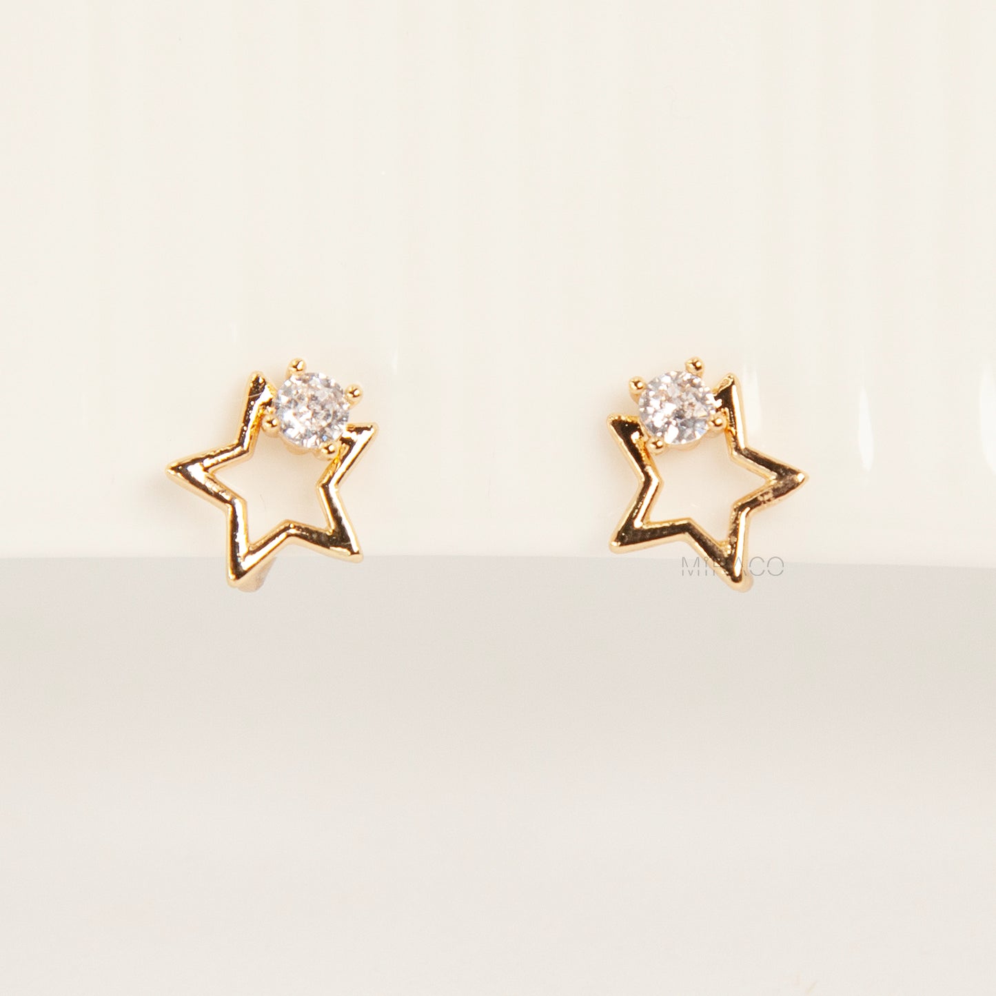 Pair of gold-tone open star-shaped clip-on earrings featuring a small clear crystal and comfortable invisible coil back closures.