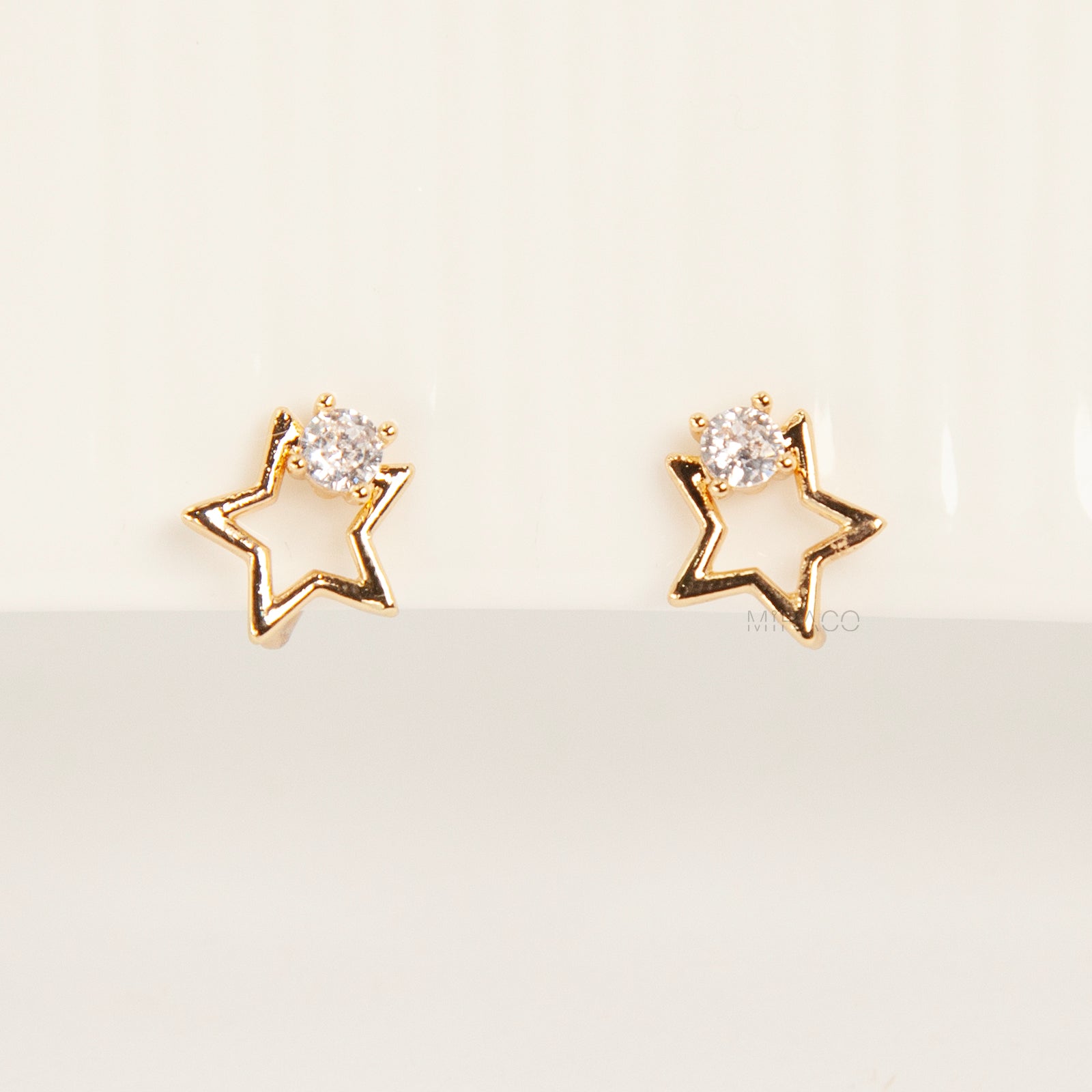 Pair of gold-tone open star-shaped clip-on earrings featuring a small clear crystal and comfortable invisible coil back closures.