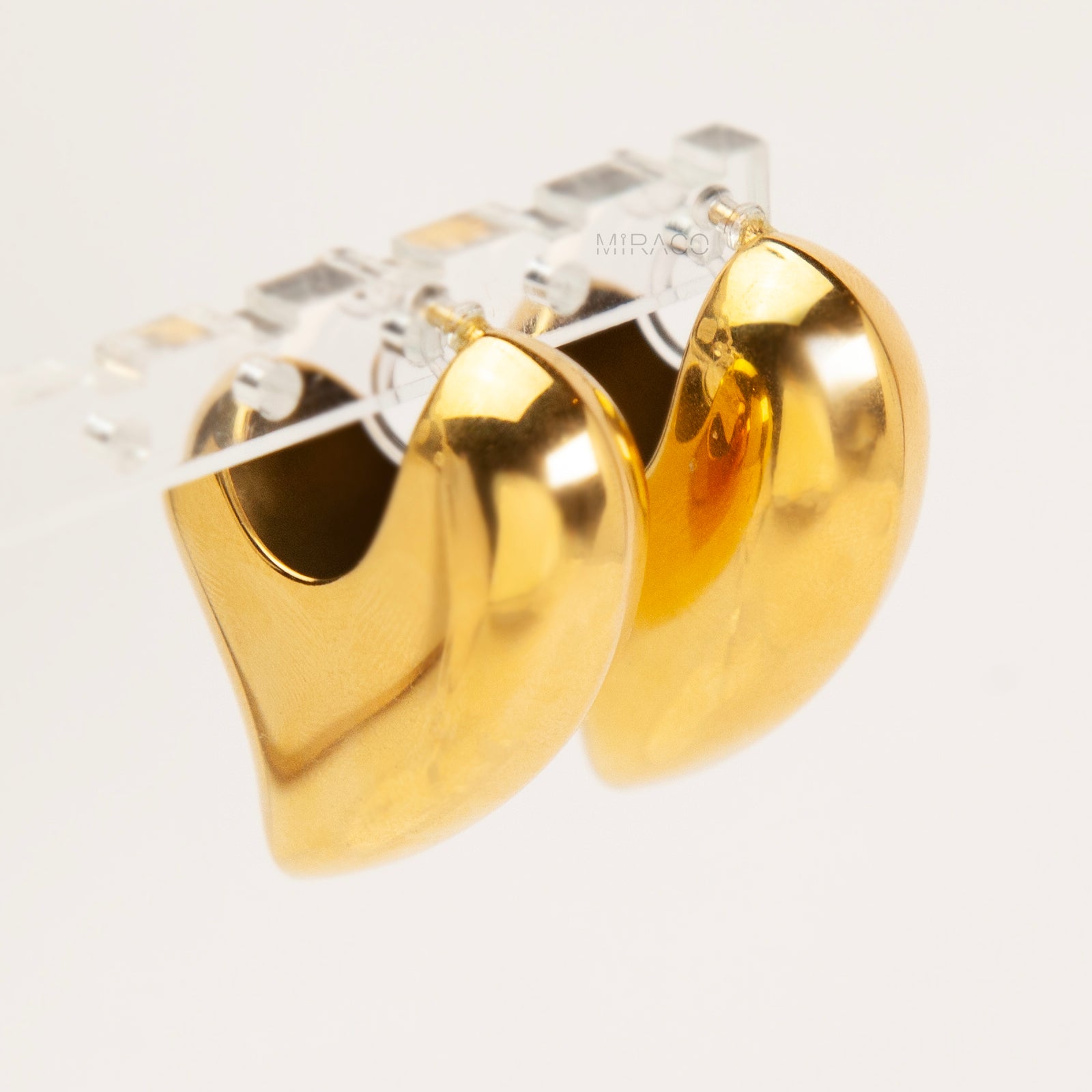 Chunky gold heart-shaped clip-on earrings with clear invisible resin backings for non-pierced ears.