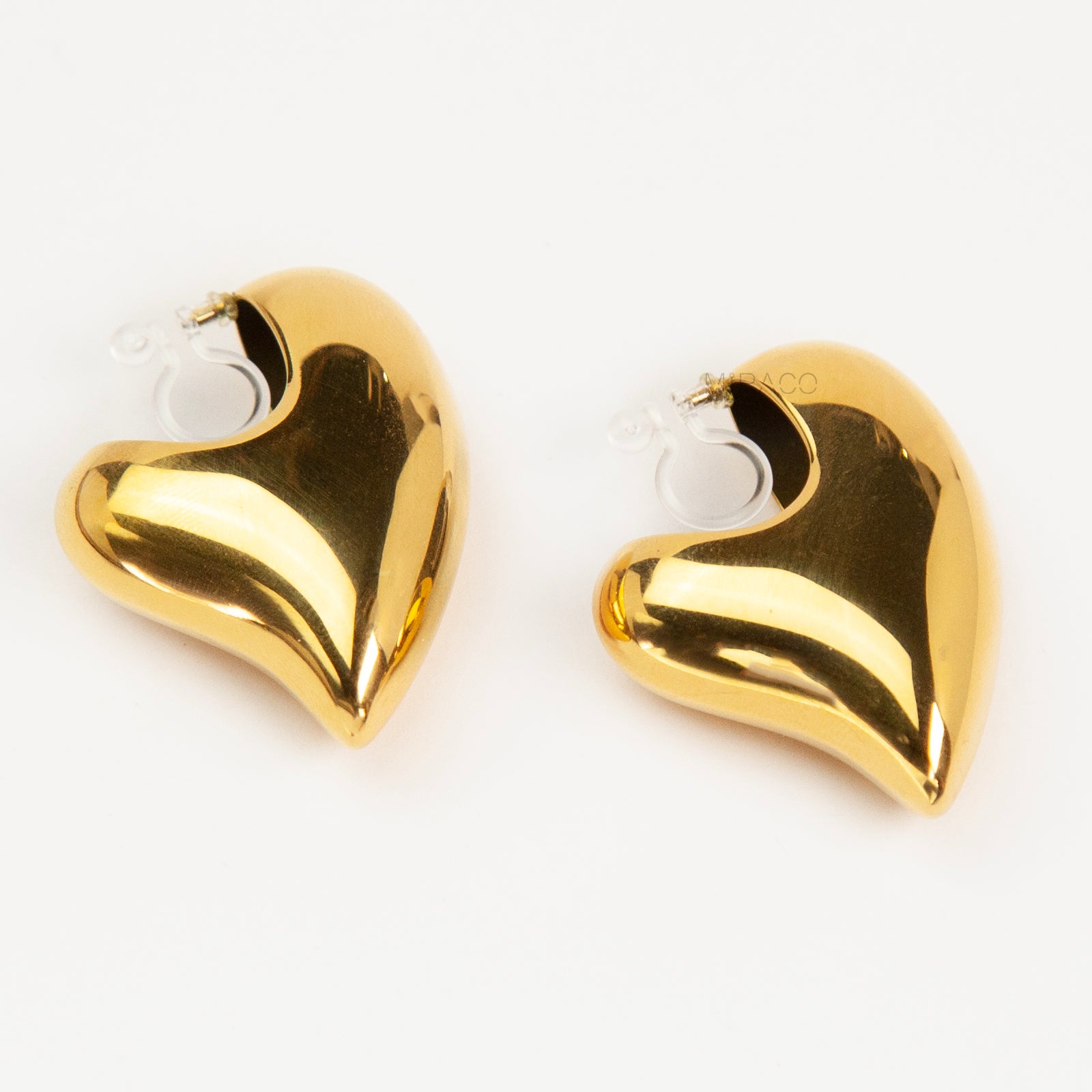 Chunky gold heart-shaped clip-on earrings with clear invisible resin backings for non-pierced ears.