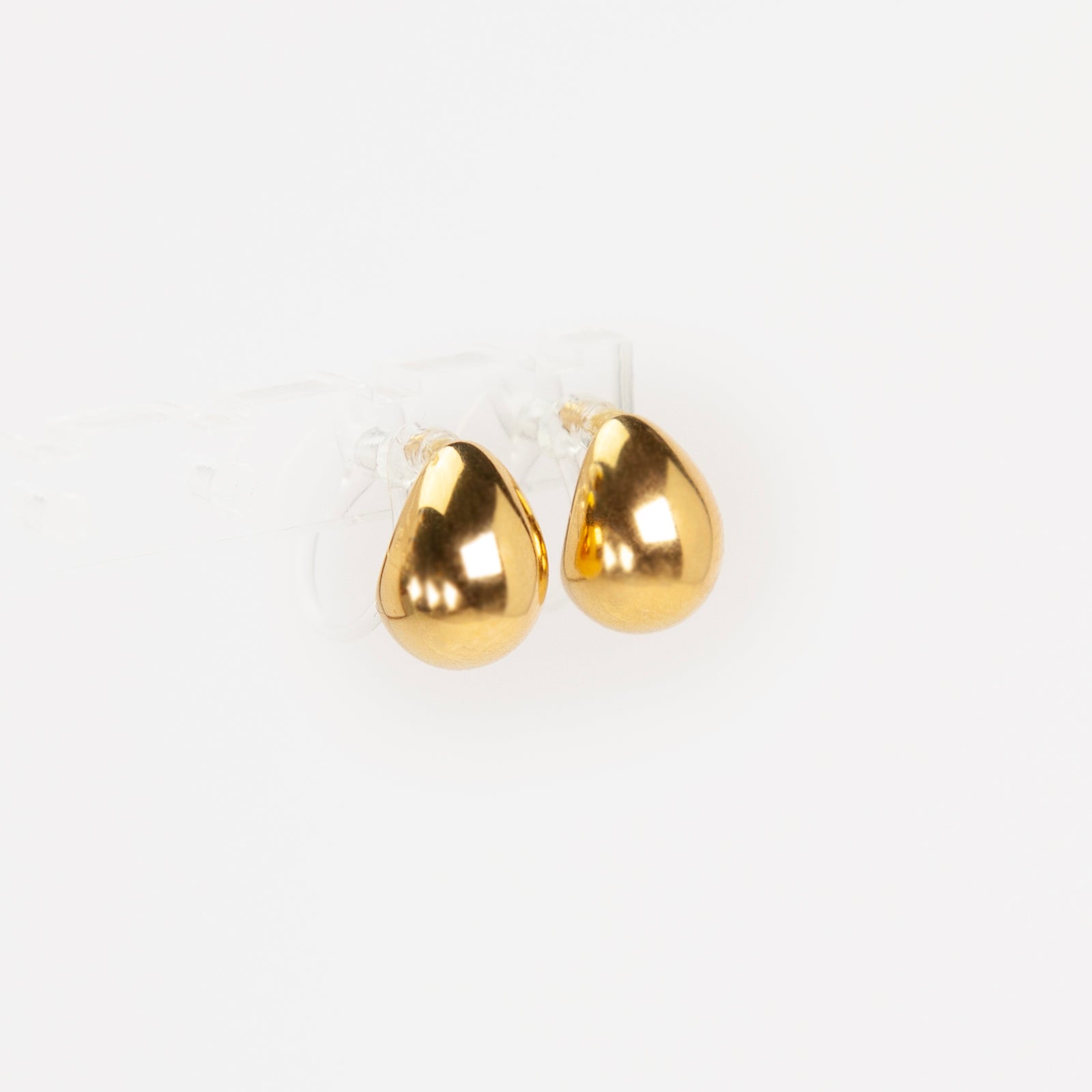 Pair of polished gold teardrop-shaped clip-on earrings with clear invisible resin backs.