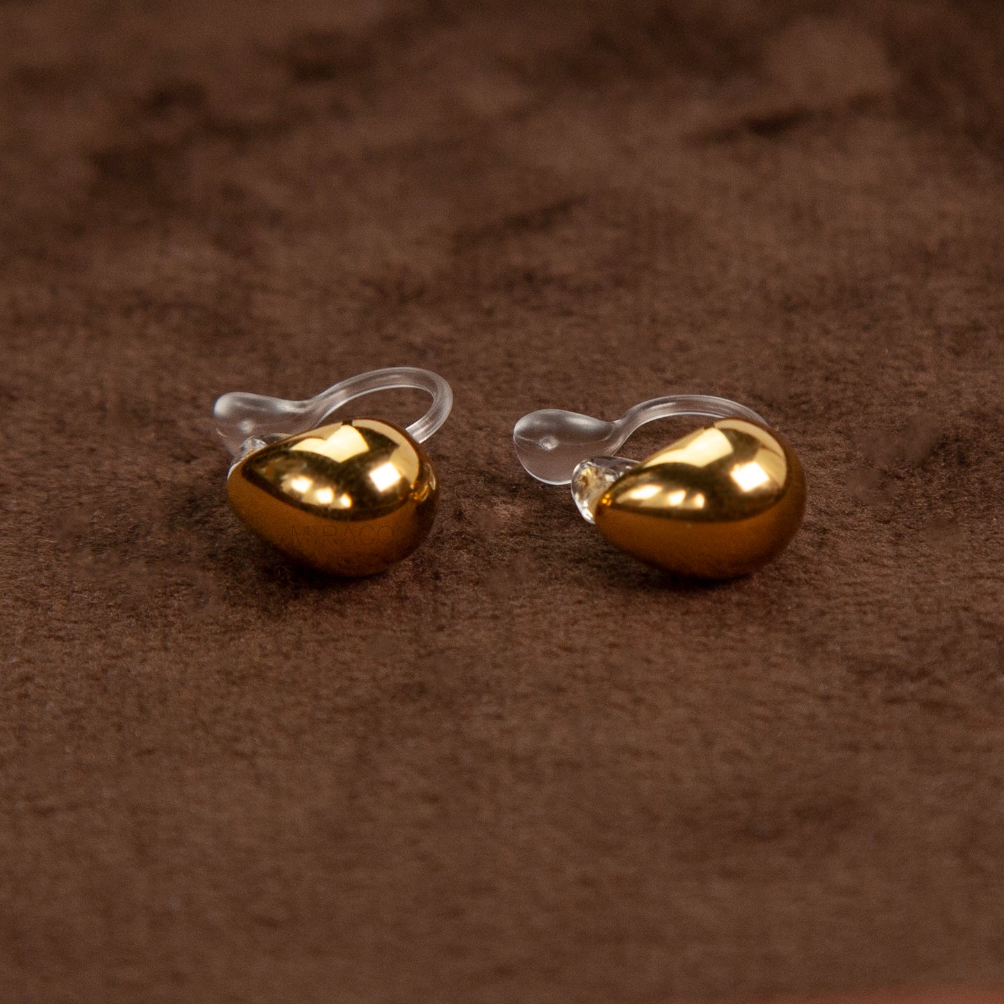 Pair of polished gold teardrop-shaped clip-on earrings with clear invisible resin backs.
