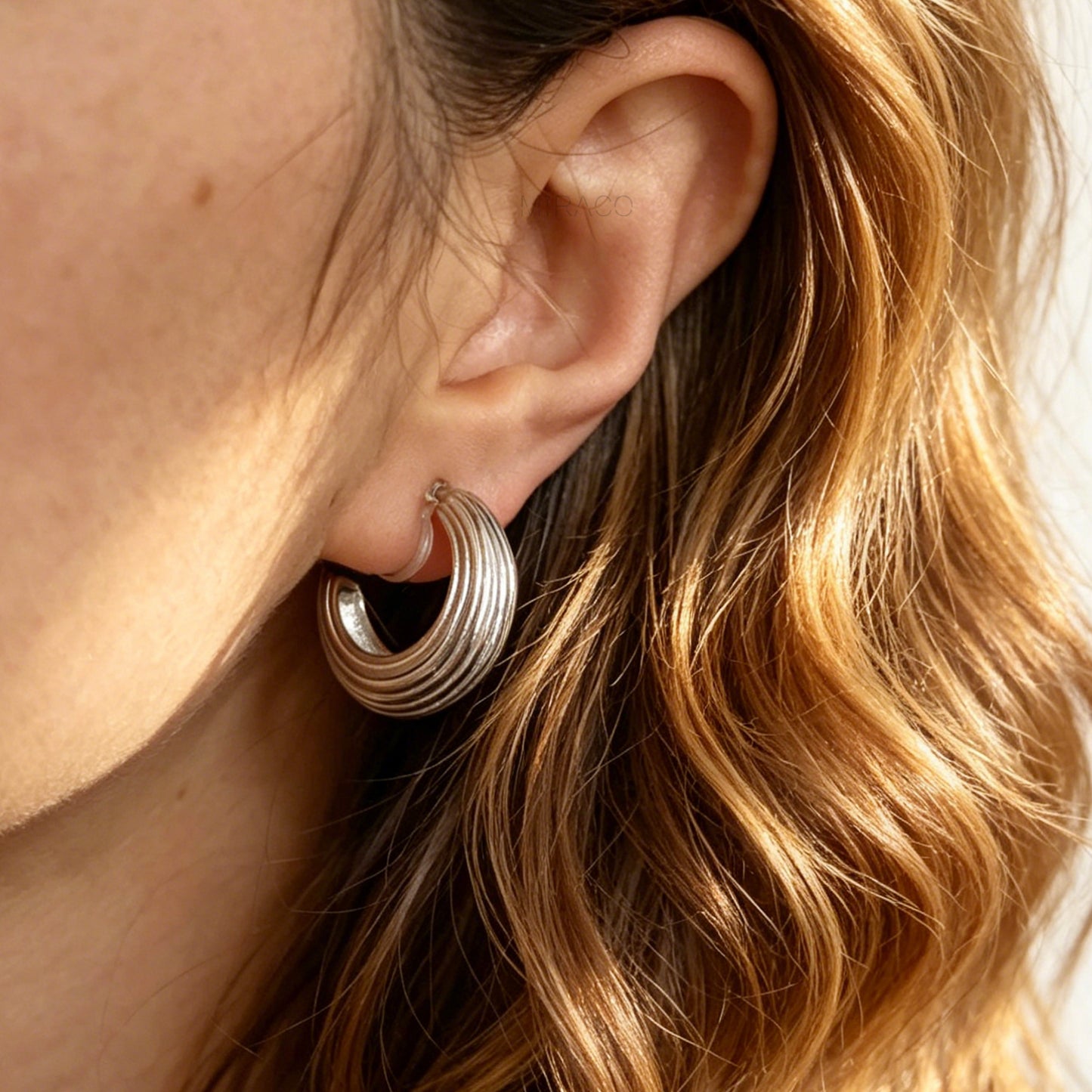 pair of ribbed C-shaped hoop earrings, featuring clear resin clip-on backs for non-pierced ears