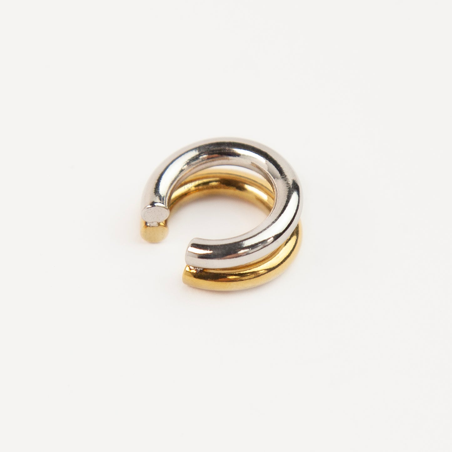 A minimalist two-tone double band ear cuff combining a polished silver hoop stacked with a gold hoop