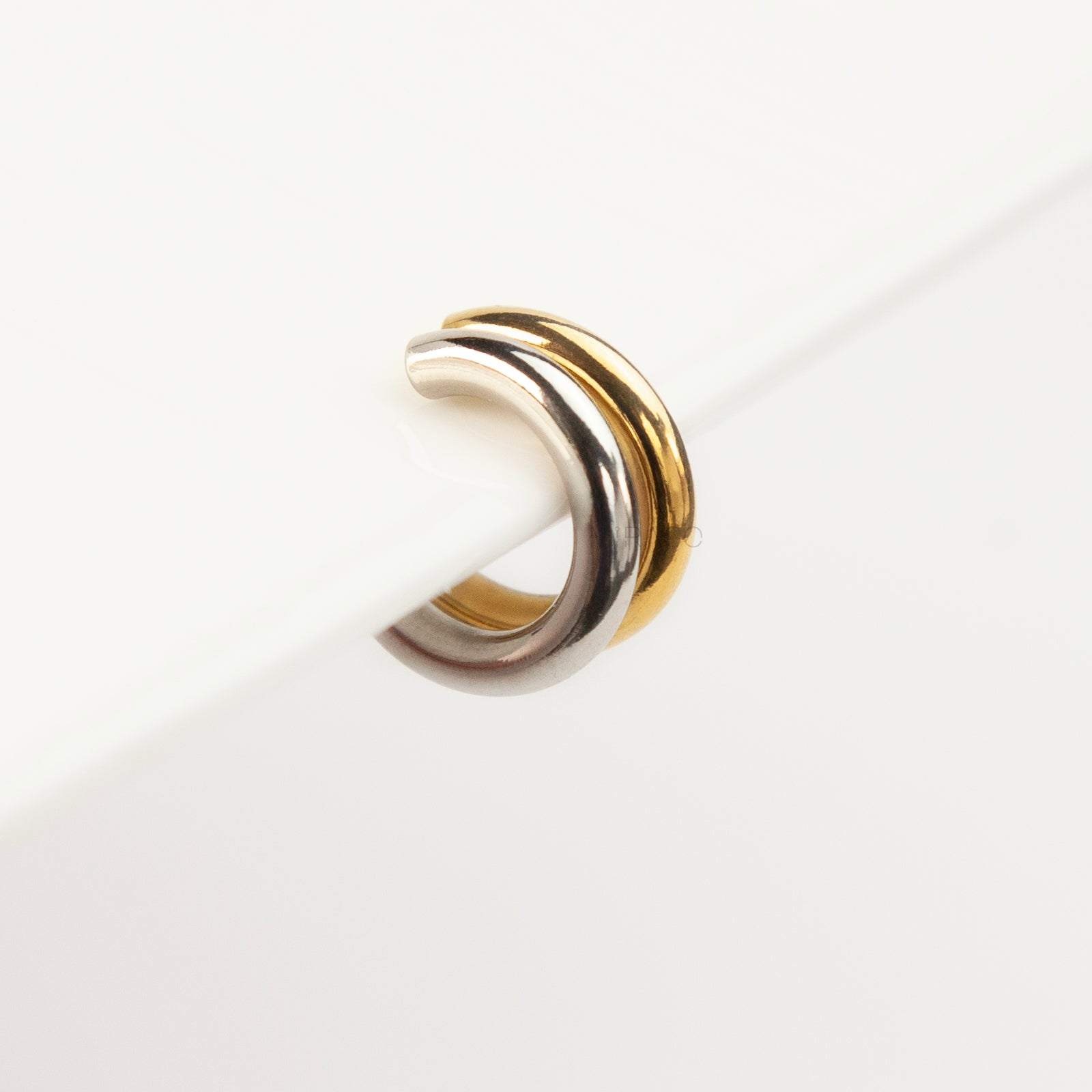 A minimalist two-tone double band ear cuff combining a polished silver hoop stacked with a gold hoop