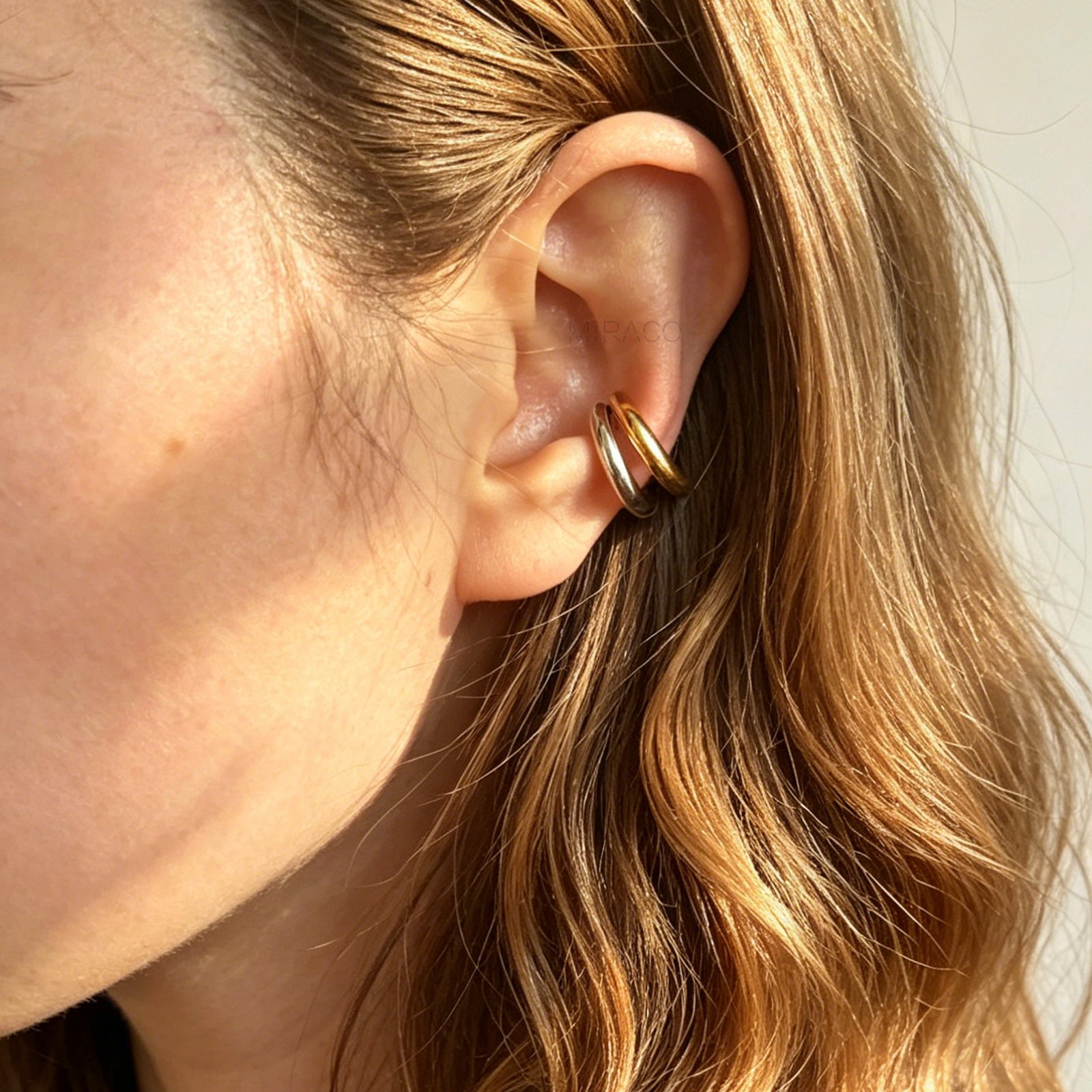 A minimalist two-tone double band ear cuff combining a polished silver hoop stacked with a gold hoop