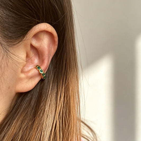 single eternity ear cuffs with bezel-set stones, gold with emerald green crystals.