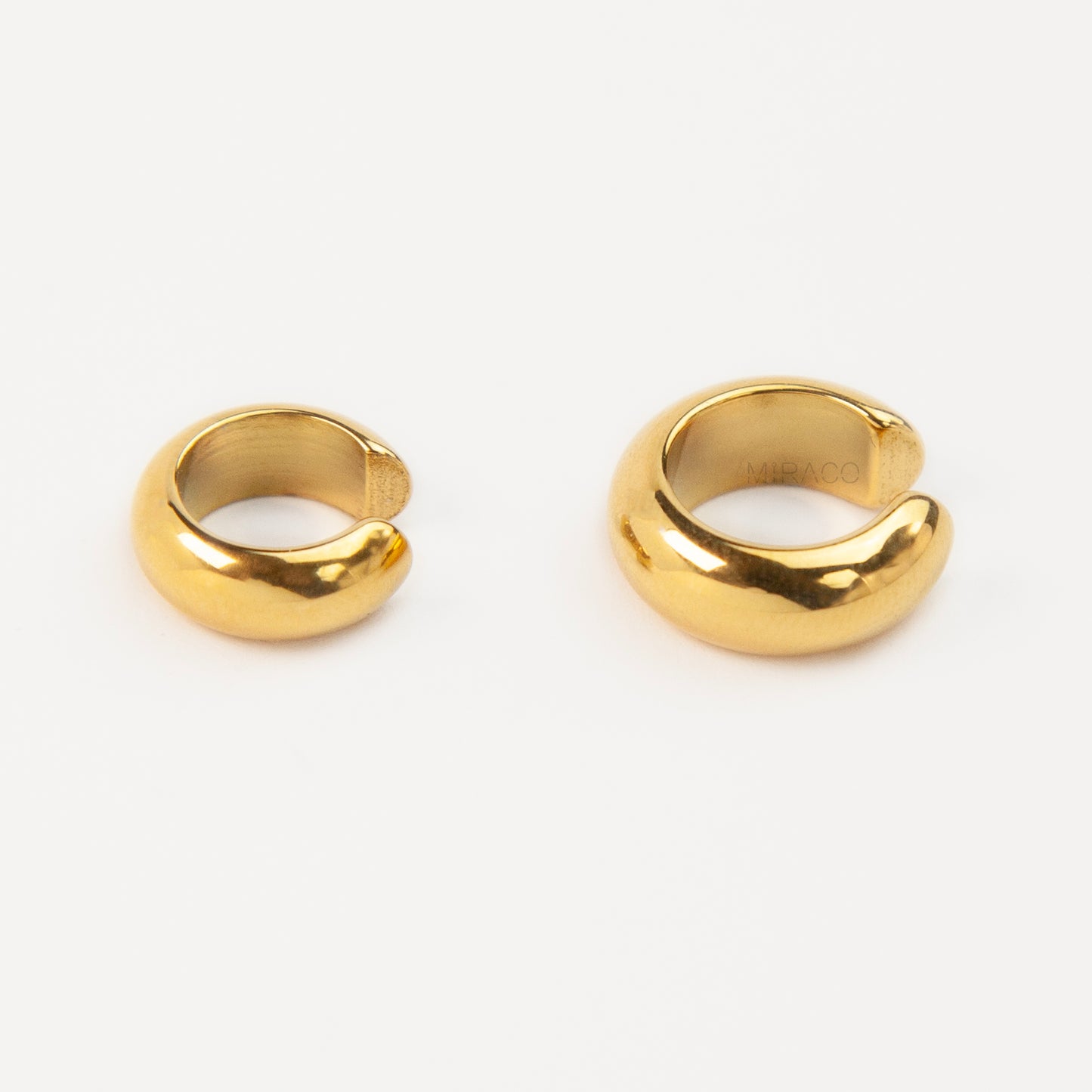 Two chunky, polished gold-tone stainless steel ear cuffs with a smooth, rounded dome design, displayed side-by-side in different sizes on a white background.