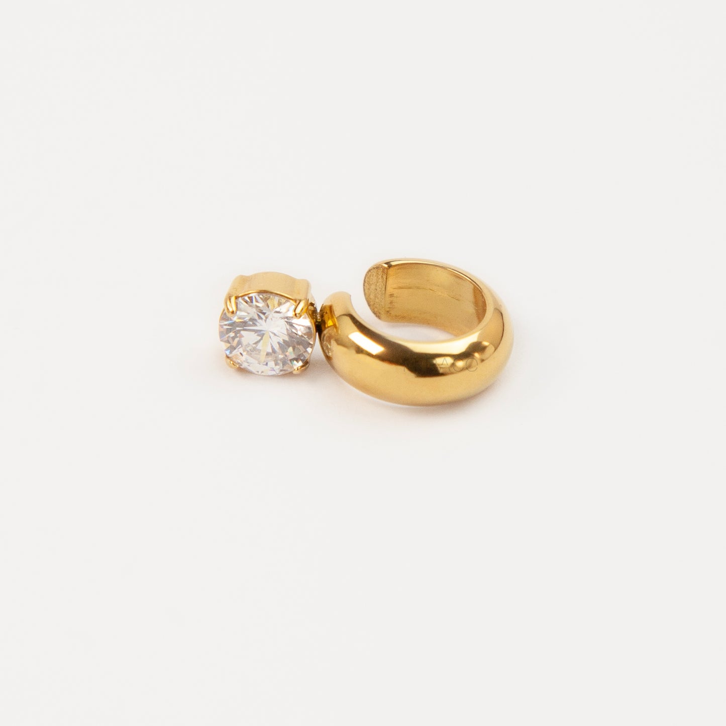 A chunky gold-tone stainless steel dome ear cuff featuring an attached round, prong-set brilliant clear crystal solitaire stone, shown close-up on a white background.