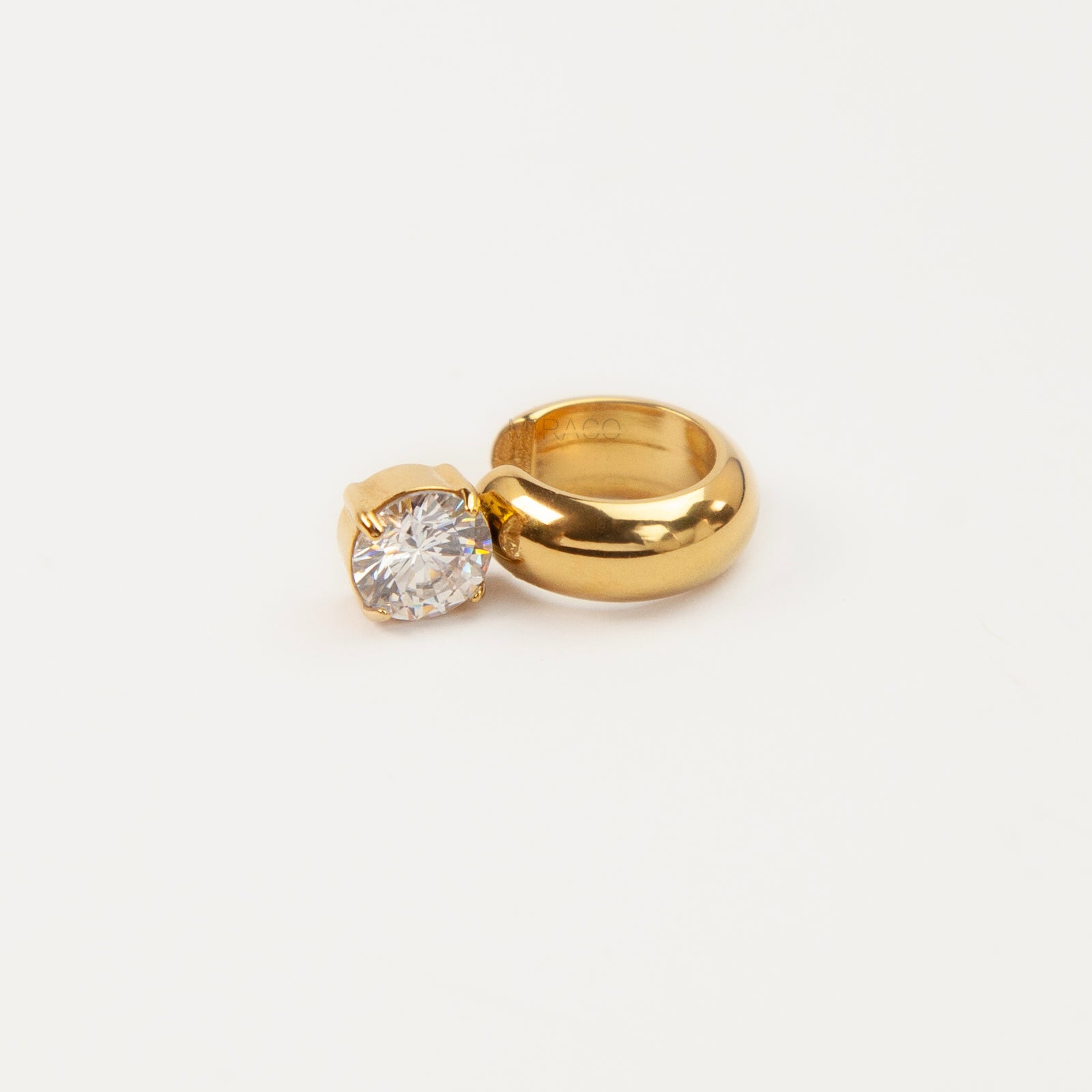 A chunky gold-tone stainless steel dome ear cuff featuring an attached round, prong-set brilliant clear crystal solitaire stone, shown close-up on a white background.