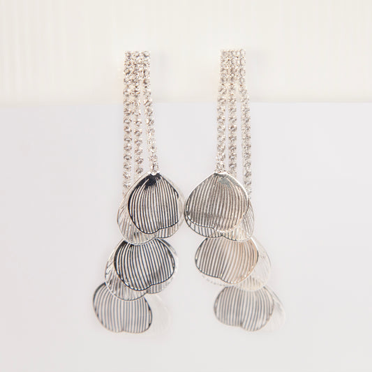 A pair of elegant silver dangle clip-on earrings from clip-on-earrings-clip475-1.jpg, featuring three rows of sparkling rhinestones cascading into textured, hollow metallic leaf elements hanging in tiers.