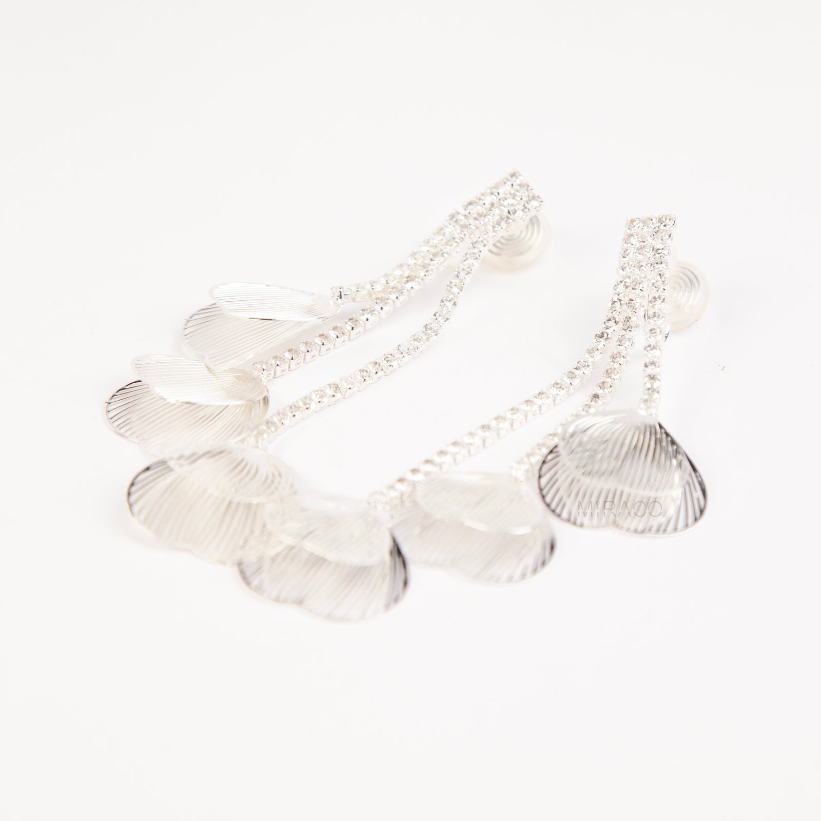 A pair of elegant silver dangle clip-on earrings, featuring three rows of sparkling rhinestones cascading into textured, hollow metallic leaf elements hanging in tiers.