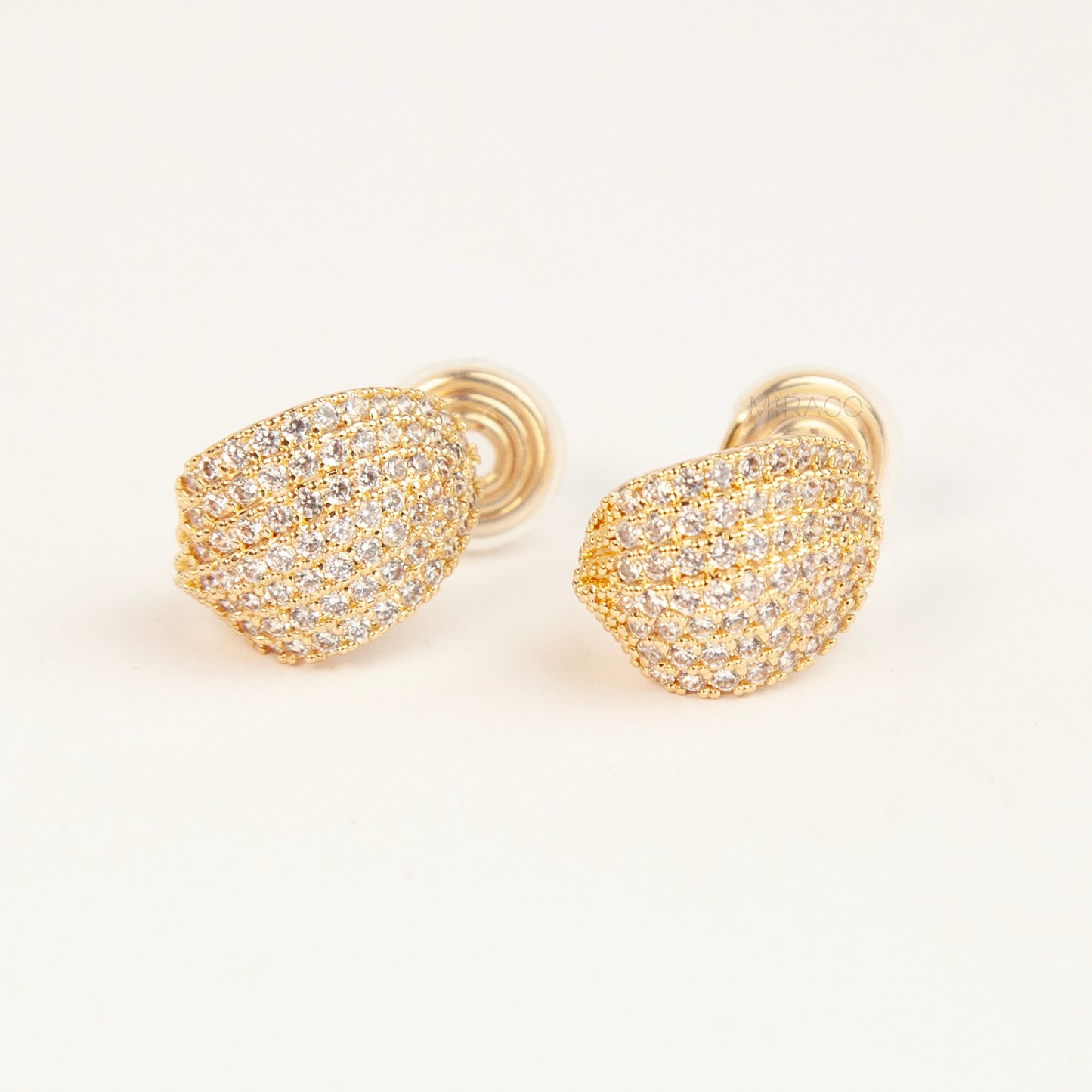 A pair of luxurious gold-plated dome clip-on earrings, heavily encrusted with rows of sparkling pave cubic zirconia crystals, featuring comfortable, adjustable spiral coil backs for non-pierced ears.