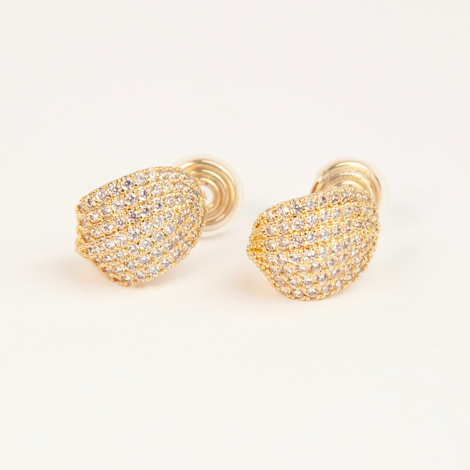 A pair of luxurious gold-plated dome clip-on earrings, heavily encrusted with rows of sparkling pave cubic zirconia crystals, featuring comfortable, adjustable spiral coil backs for non-pierced ears.