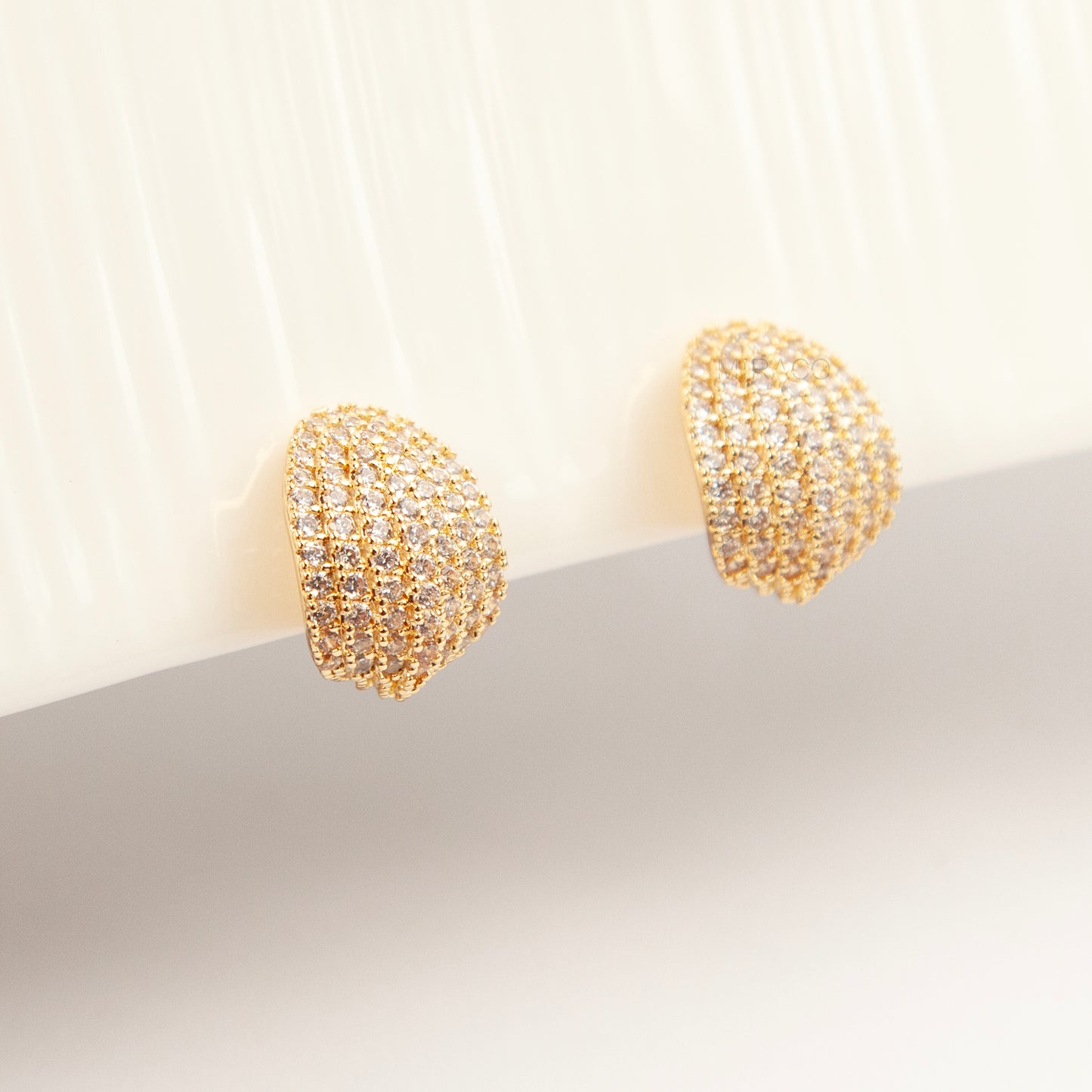 A pair of luxurious gold-plated dome clip-on earrings, heavily encrusted with rows of sparkling pave cubic zirconia crystals, featuring comfortable, adjustable spiral coil backs for non-pierced ears.