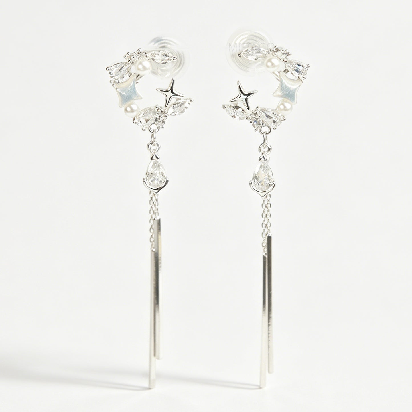 A pair of elegant silver celestial dangle clip-on earrings, featuring a crescent moon and star design accented with marquise crystals and tiny pearls, cascading into a teardrop gemstone and sleek, vertical metallic bar tassels on comfortable coil backs.