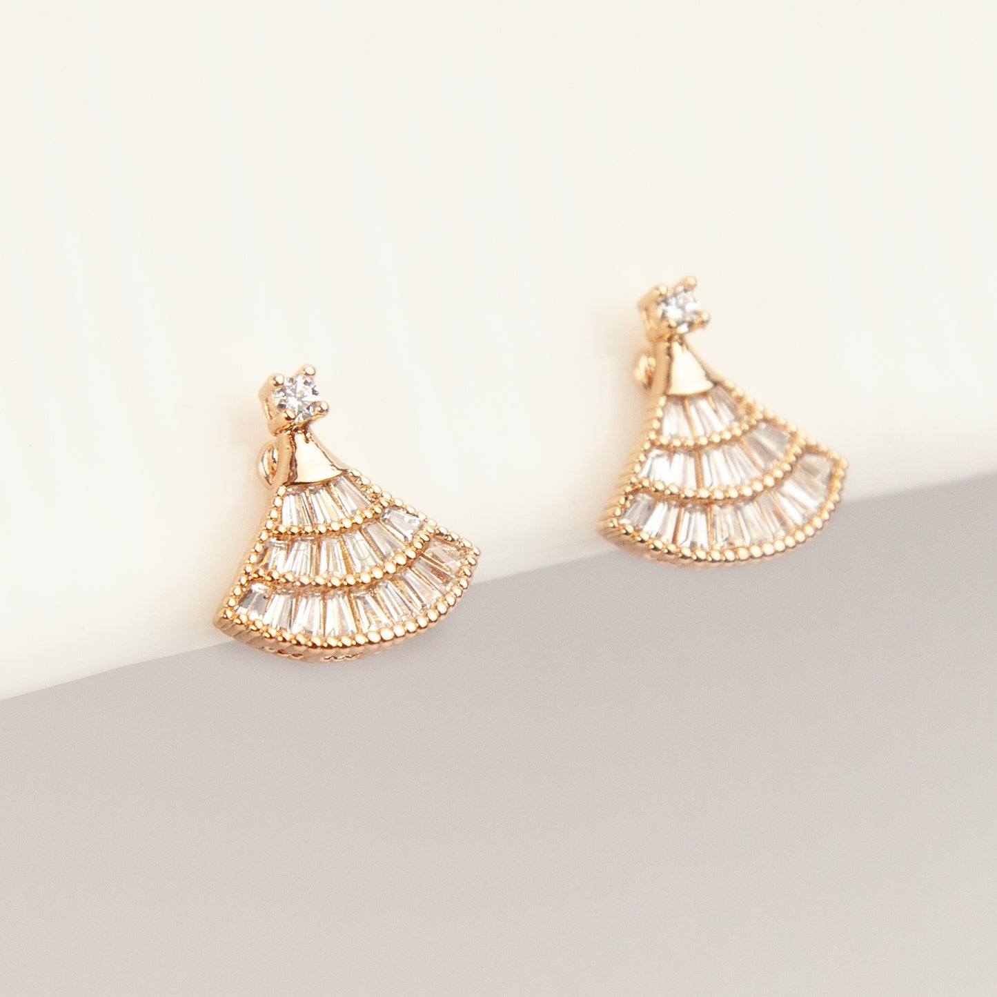 A pair of gold Art Deco fan-shaped clip-on earrings, detailed with tiered baguette crystals and fitted with comfortable coil backs featuring clear comfort cushions.