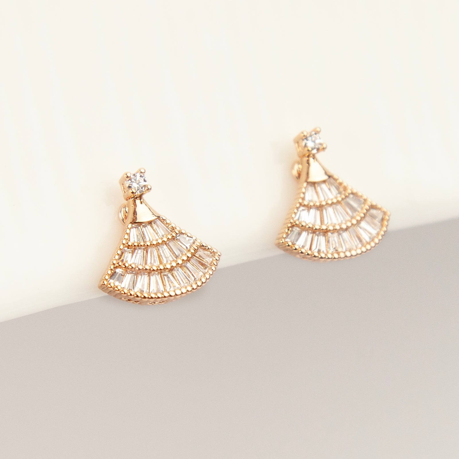 A pair of gold Art Deco fan-shaped clip-on earrings, detailed with tiered baguette crystals and fitted with comfortable coil backs featuring clear comfort cushions.