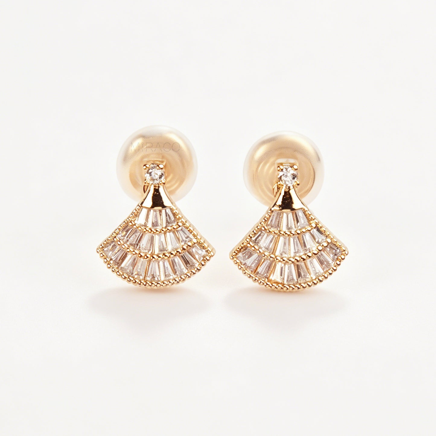 A pair of gold Art Deco fan-shaped clip-on earrings, detailed with tiered baguette crystals and fitted with comfortable coil backs featuring clear comfort cushions.