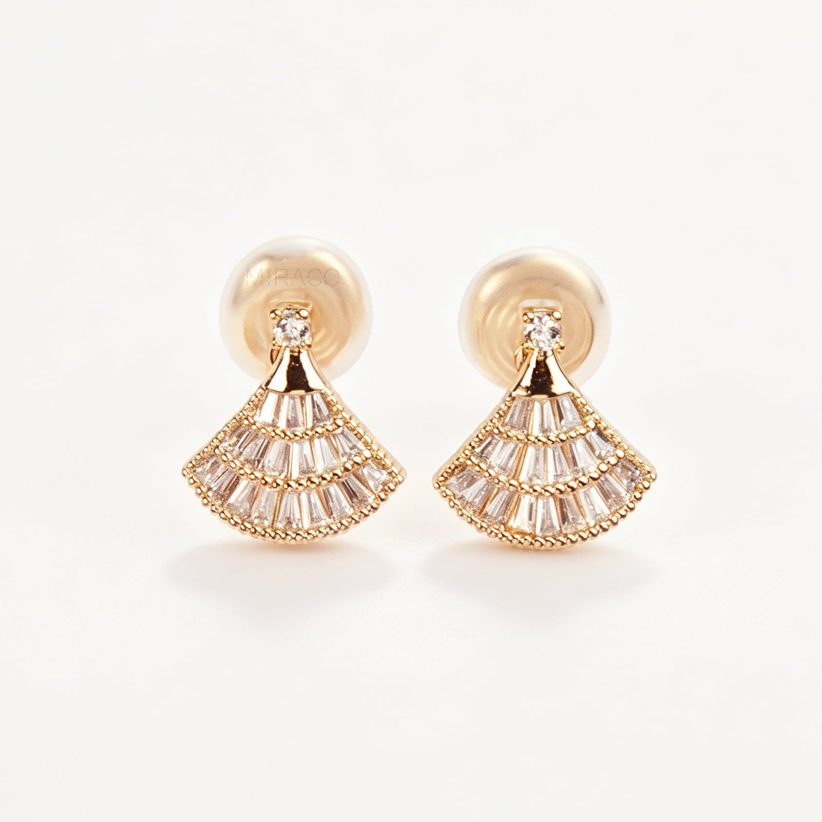 A pair of gold Art Deco fan-shaped clip-on earrings, detailed with tiered baguette crystals and fitted with comfortable coil backs featuring clear comfort cushions.