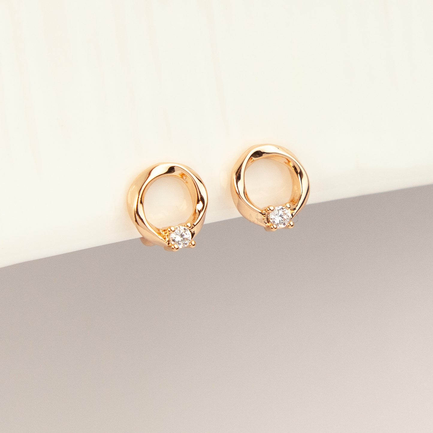 A pair of gold open circle stud clip-on earrings accented with a single sparkling round crystal and fitted with comfortable coil backs with clear silicone cushions.