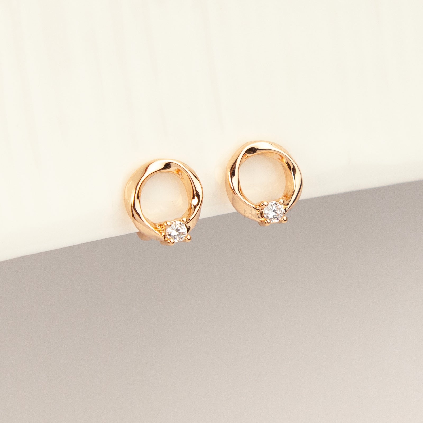 A pair of gold open circle stud clip-on earrings accented with a single sparkling round crystal and fitted with comfortable coil backs with clear silicone cushions.