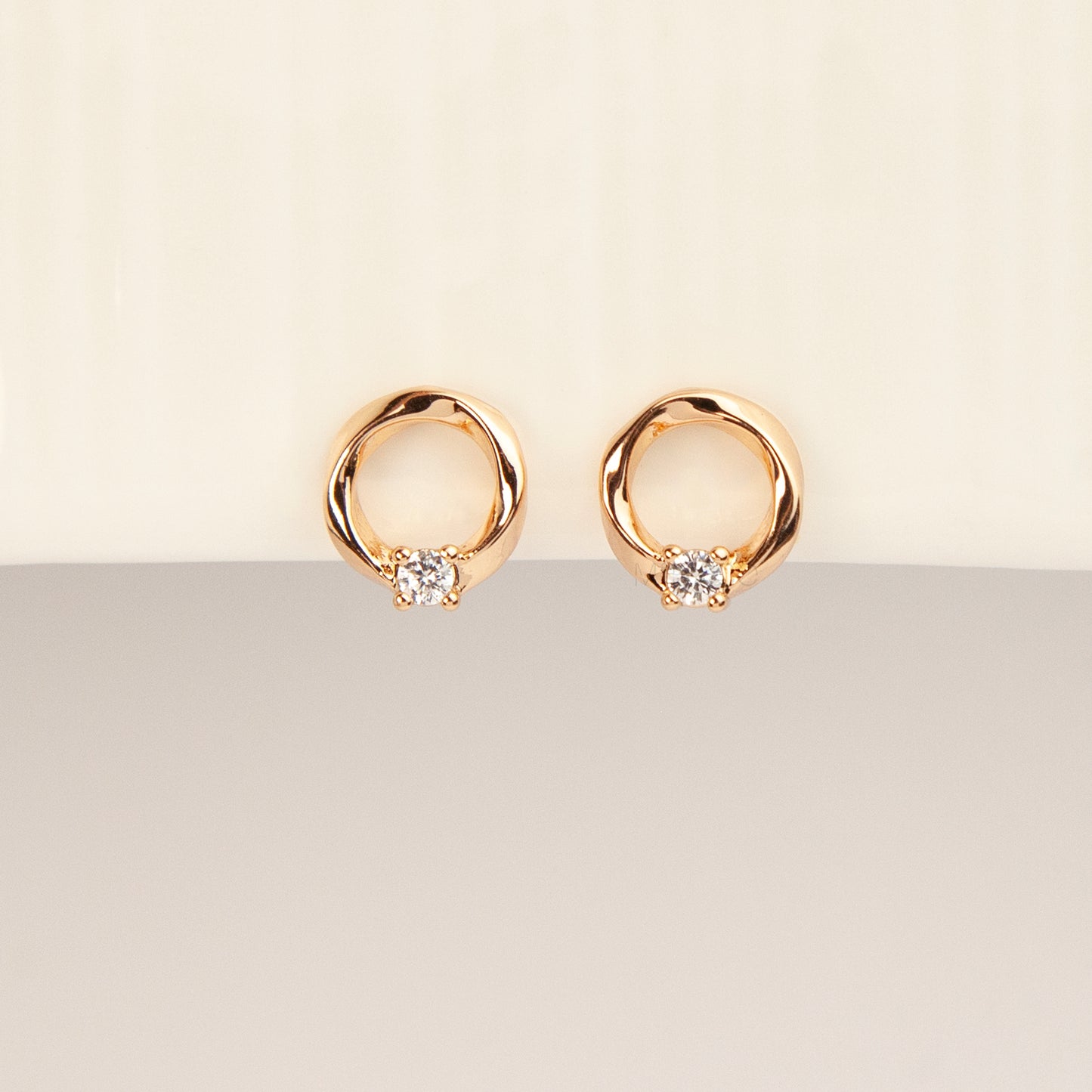 A pair of gold open circle stud clip-on earrings accented with a single sparkling round crystal and fitted with comfortable coil backs with clear silicone cushions.