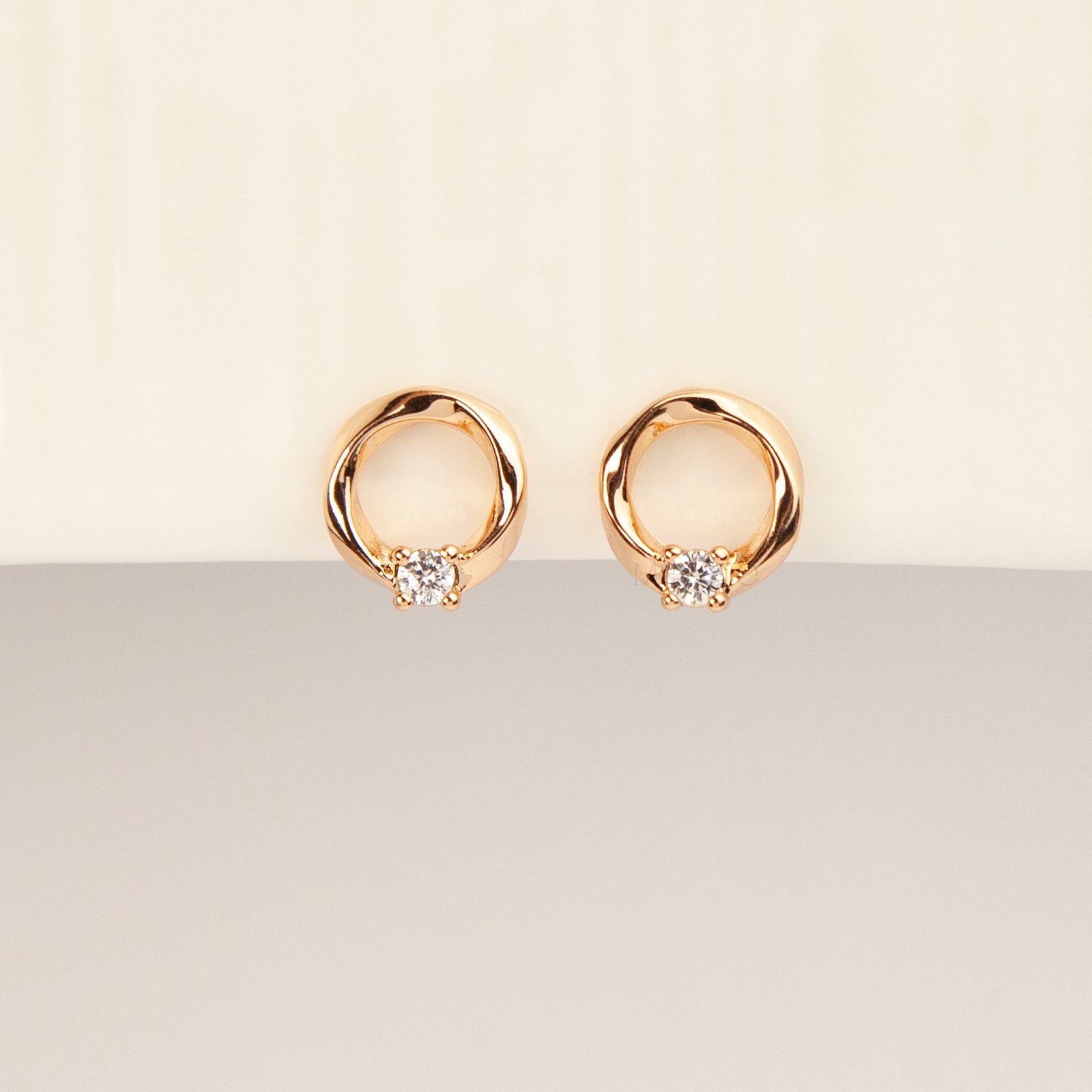 A pair of gold open circle stud clip-on earrings accented with a single sparkling round crystal and fitted with comfortable coil backs with clear silicone cushions.