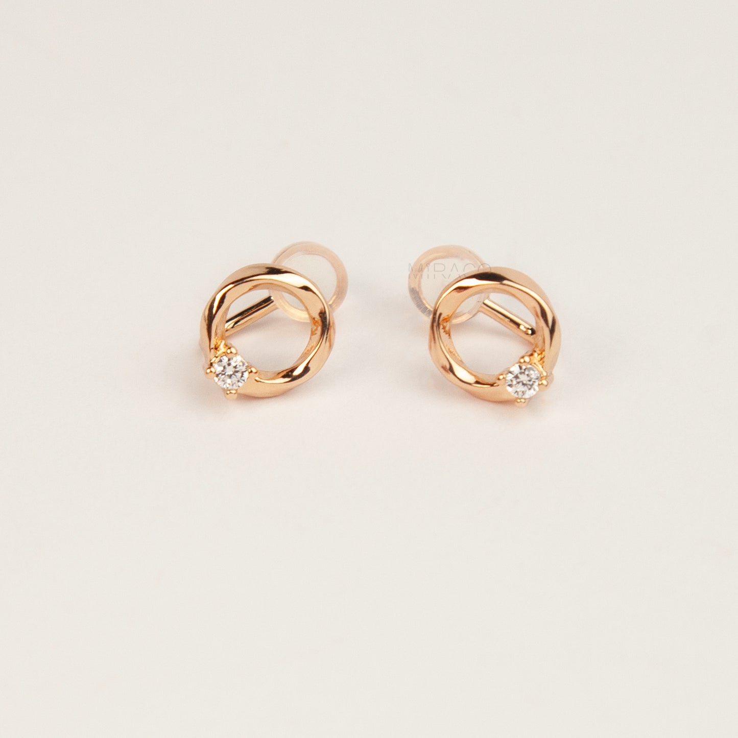 A pair of gold open circle stud clip-on earrings accented with a single sparkling round crystal and fitted with comfortable coil backs with clear silicone cushions.