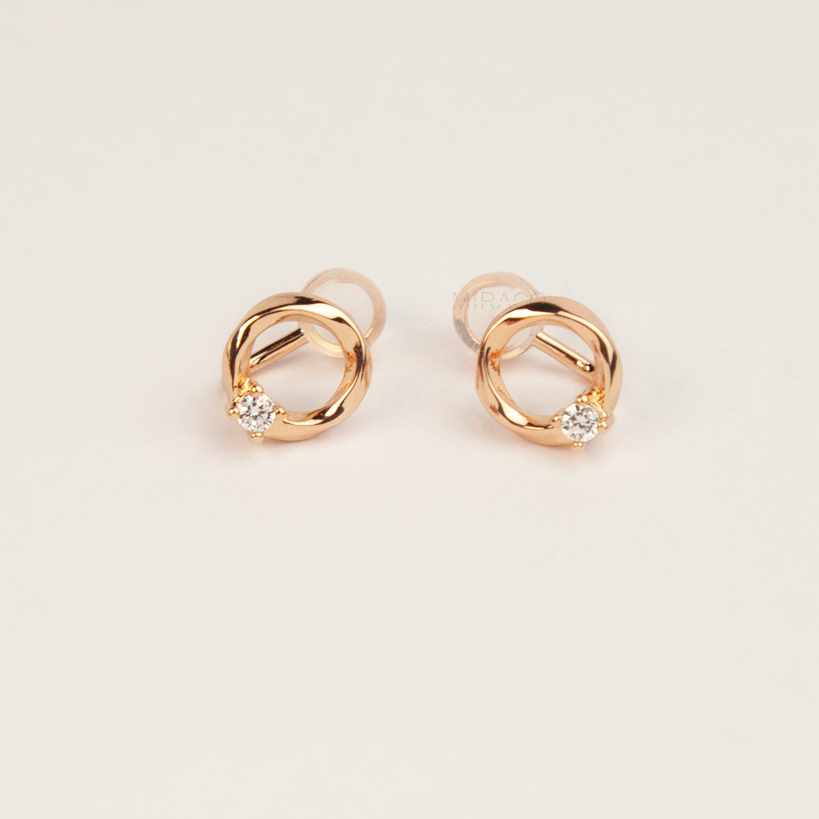 A pair of gold open circle stud clip-on earrings accented with a single sparkling round crystal and fitted with comfortable coil backs with clear silicone cushions.
