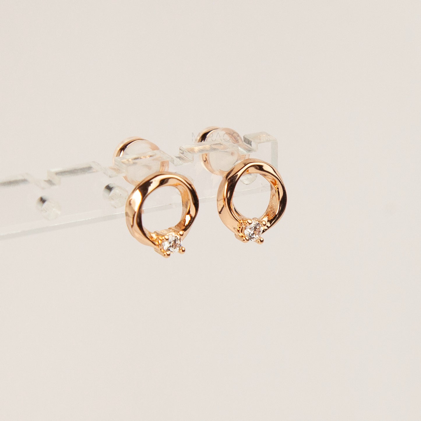 A pair of gold open circle stud clip-on earrings accented with a single sparkling round crystal and fitted with comfortable coil backs with clear silicone cushions.