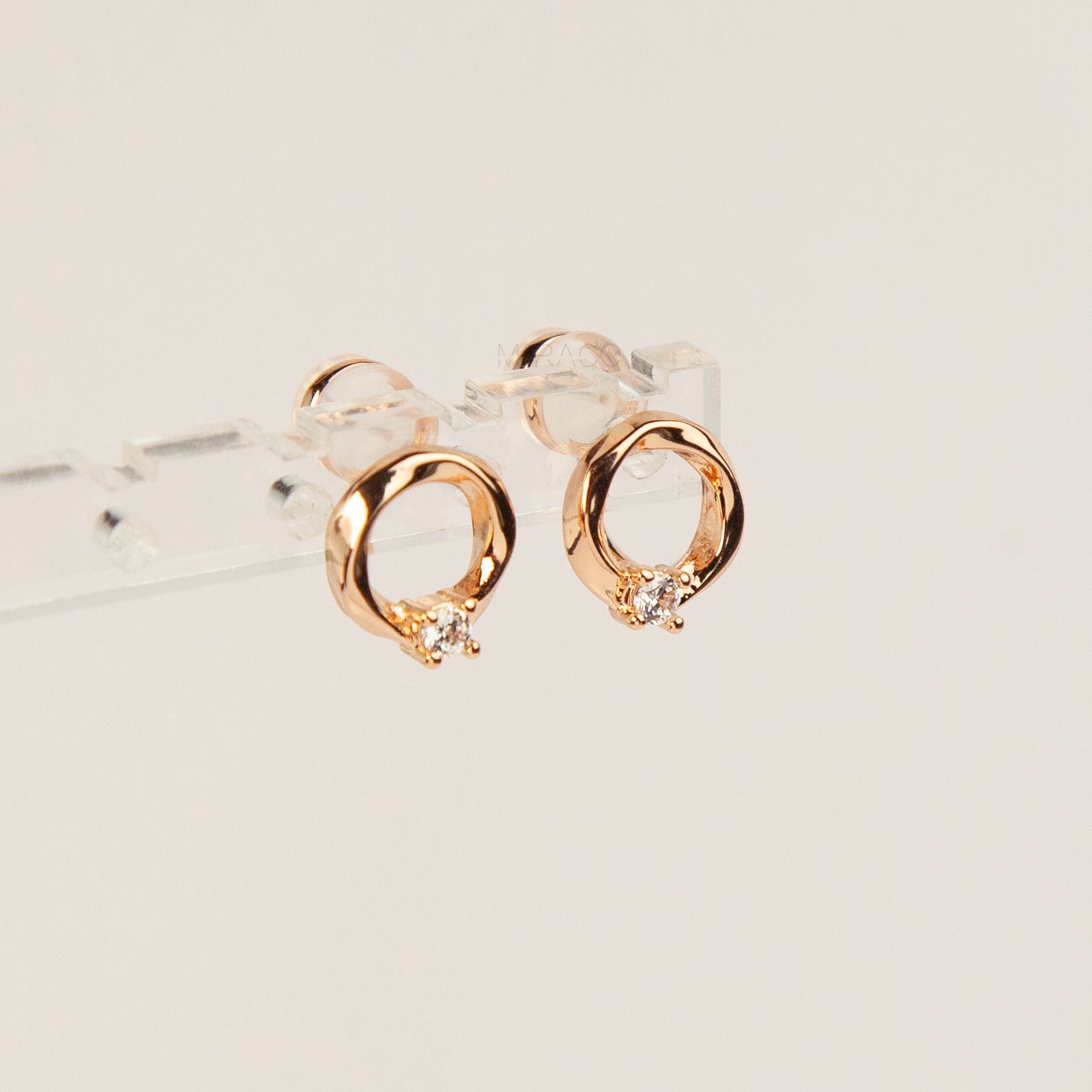 A pair of gold open circle stud clip-on earrings accented with a single sparkling round crystal and fitted with comfortable coil backs with clear silicone cushions.