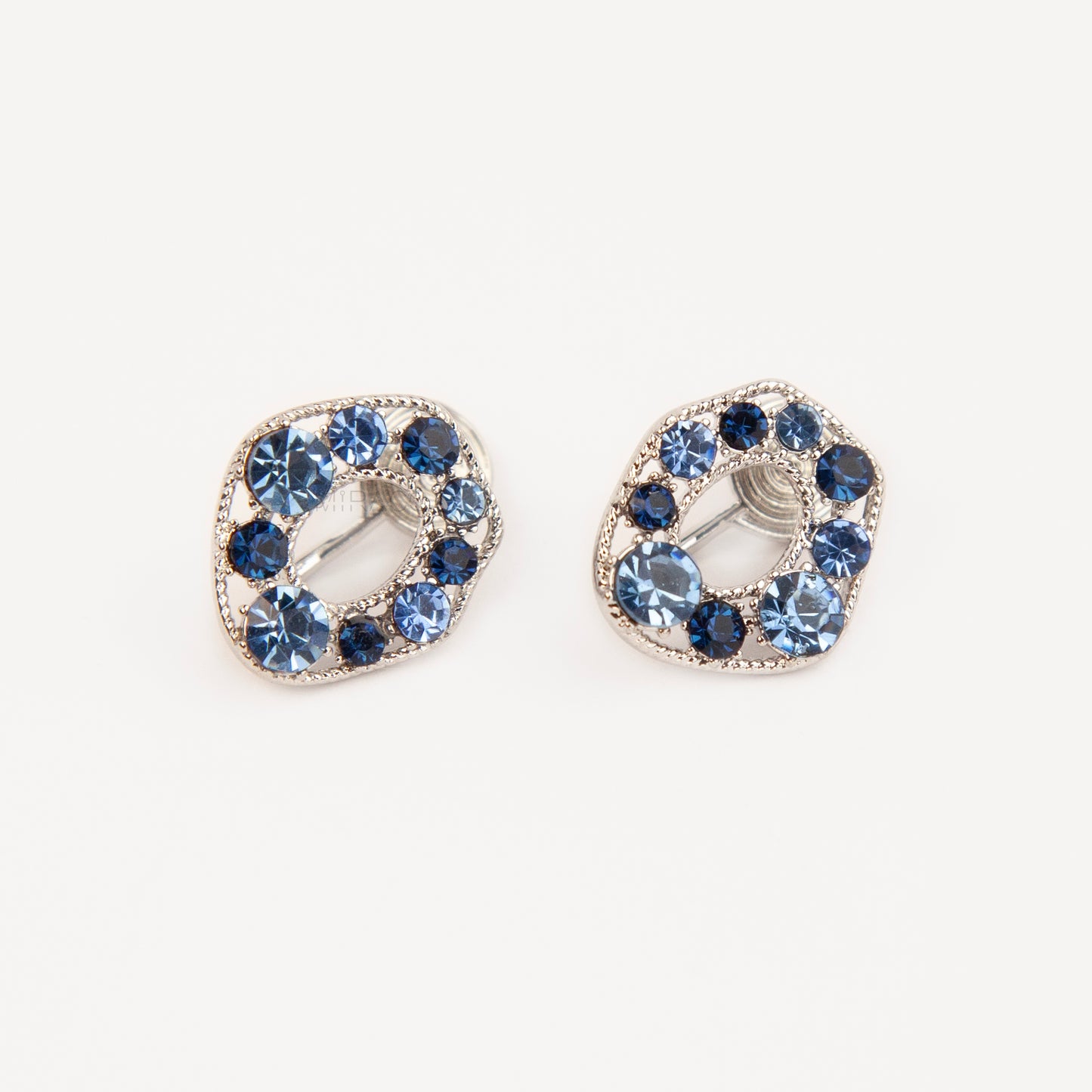 Pair of oval silver-tone non-pierced clip-on earrings with coil backs, set with sparkling dark and light blue crystals.