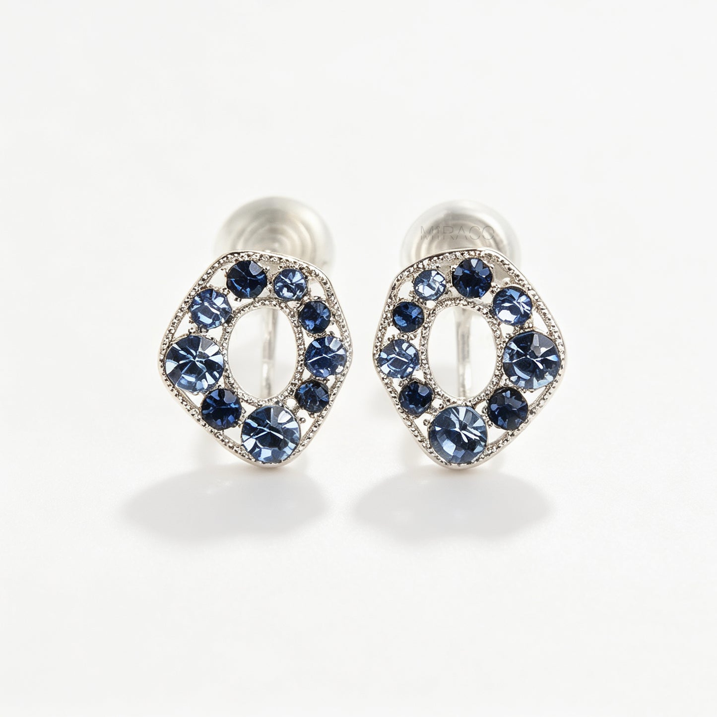 Pair of oval silver-tone non-pierced clip-on earrings with coil backs, set with sparkling dark and light blue crystals.