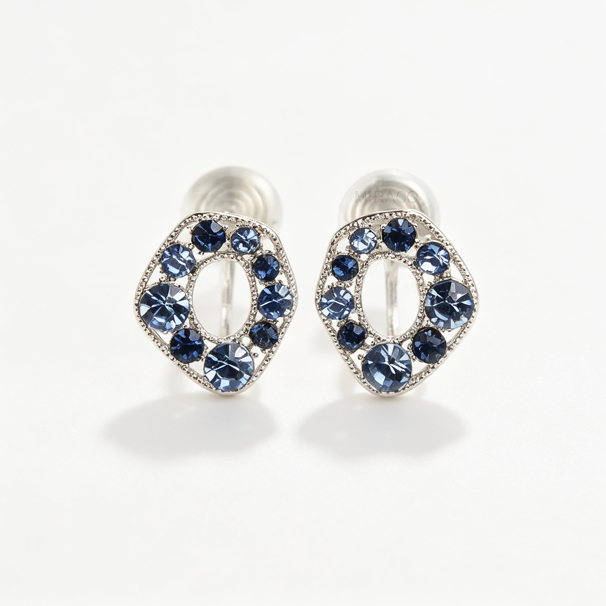 Pair of oval silver-tone non-pierced clip-on earrings with coil backs, set with sparkling dark and light blue crystals.