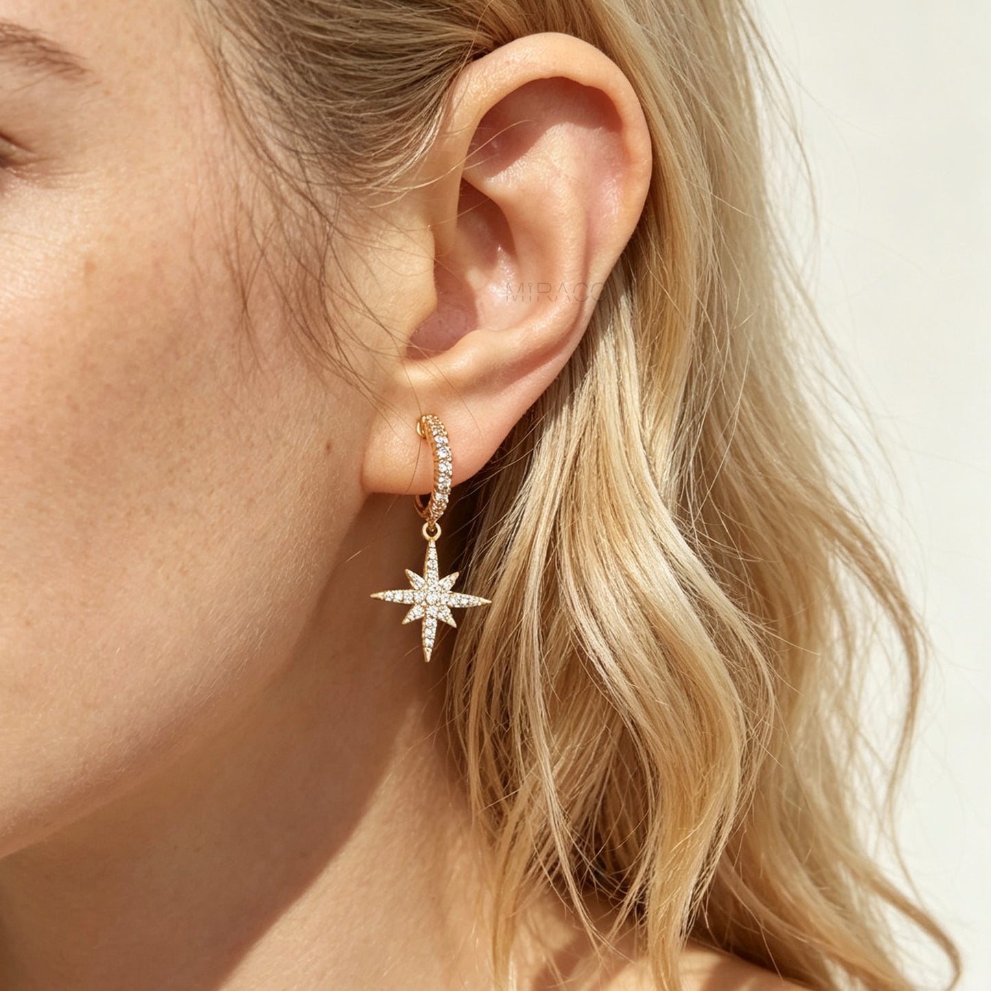 Gold and silver non-pierced clip-on dangle earrings with coil backs, featuring cubic zirconia paved hoops and celestial starburst drops.