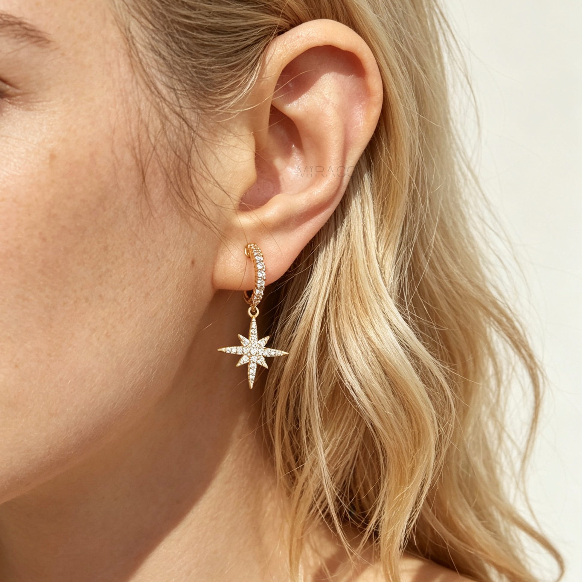 Gold and silver non-pierced clip-on dangle earrings with coil backs, featuring cubic zirconia paved hoops and celestial starburst drops.