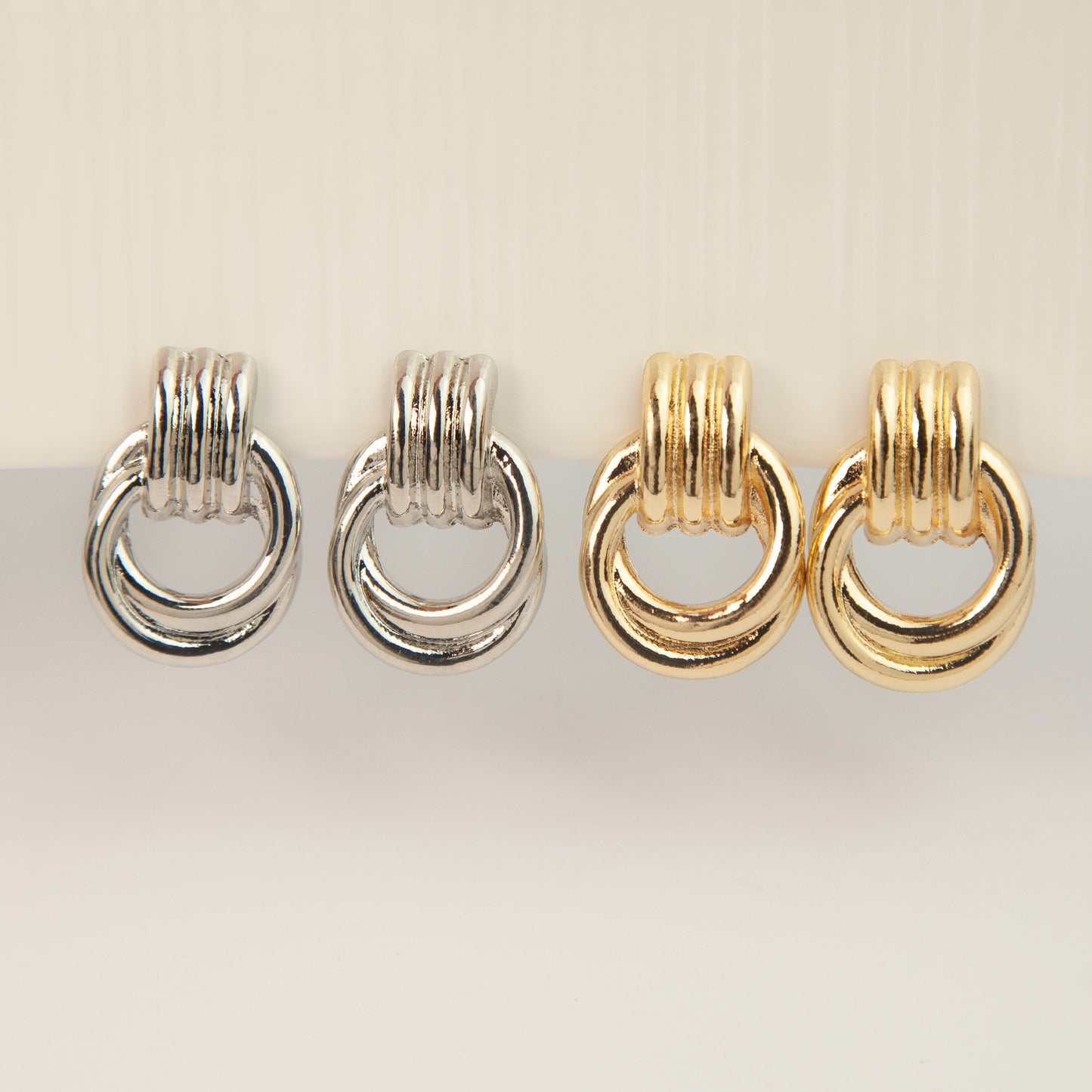 Gold and silver non-pierced double ring door knocker clip-on earrings with ribbed texture tops and mini clip backs displayed side by side.