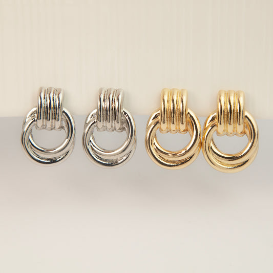 Gold and silver non-pierced double ring door knocker clip-on earrings with ribbed texture tops and mini clip backs displayed side by side.
