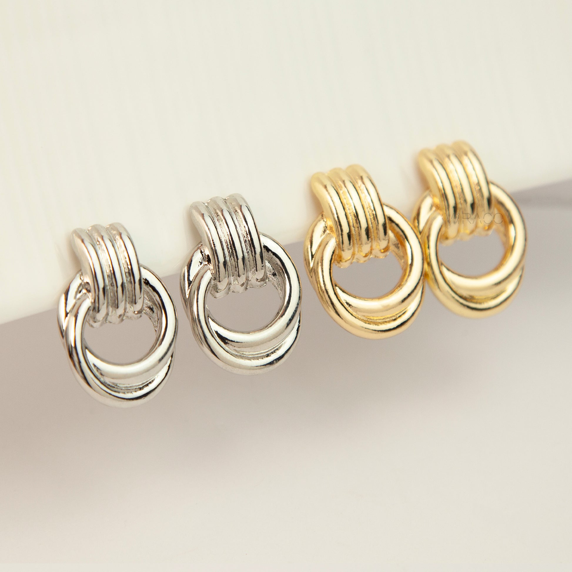 Gold and silver non-pierced double ring door knocker clip-on earrings with ribbed texture tops and mini clip backs displayed side by side.