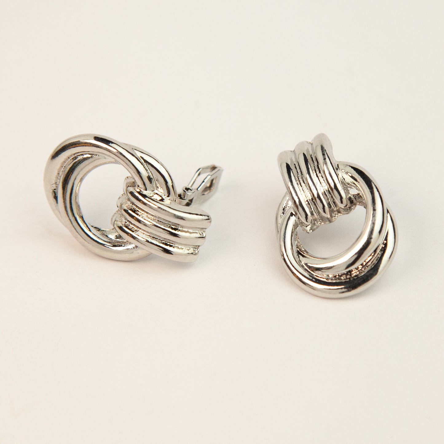 Gold and silver non-pierced double ring door knocker clip-on earrings with ribbed texture tops and mini clip backs displayed side by side.