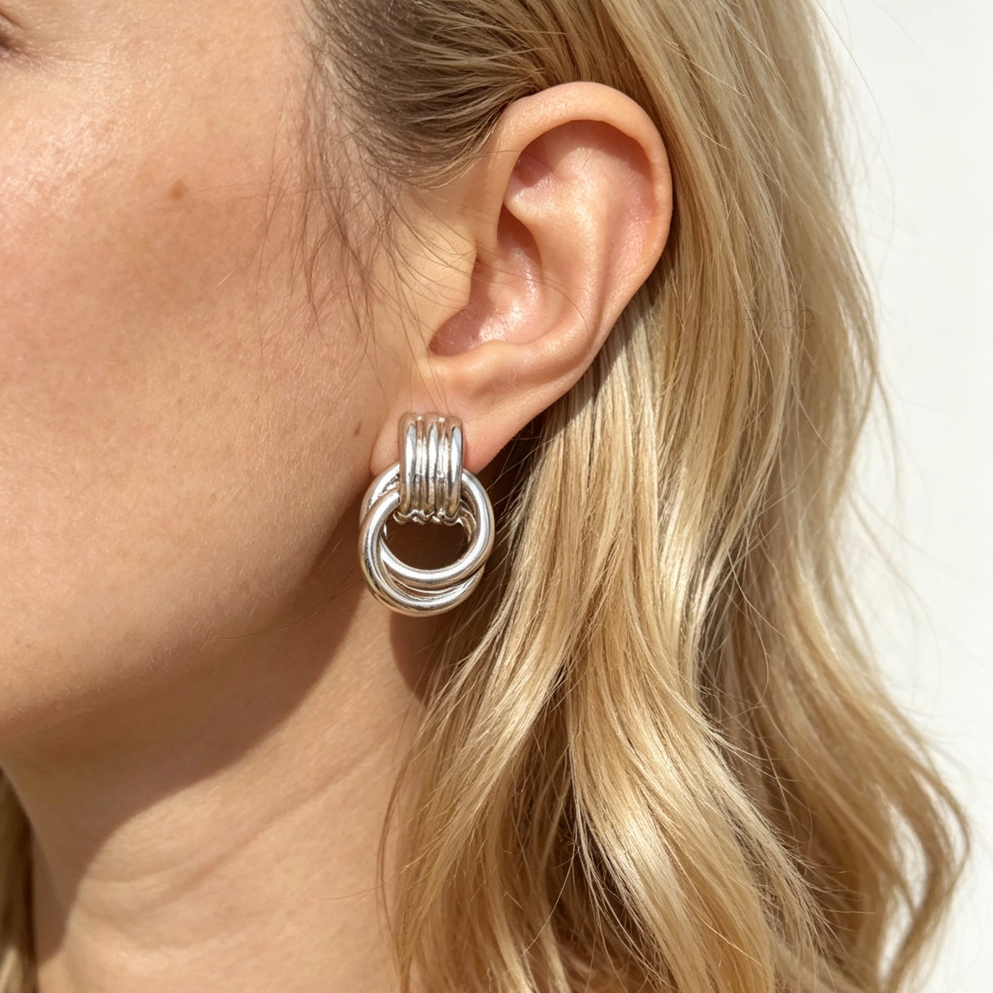 Gold and silver non-pierced double ring door knocker clip-on earrings with ribbed texture tops and mini clip backs displayed side by side.