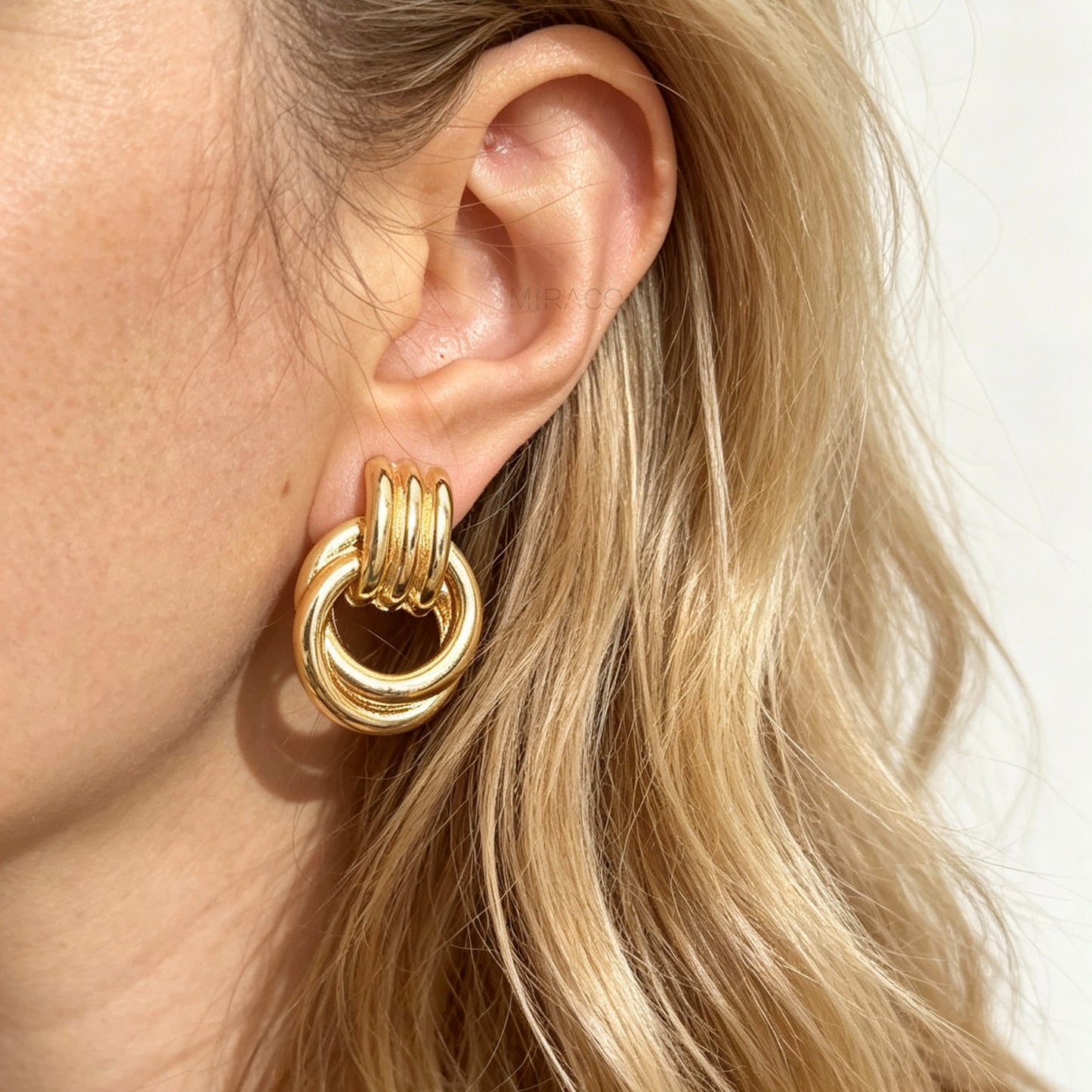 Gold and silver non-pierced double ring door knocker clip-on earrings with ribbed texture tops and mini clip backs displayed side by side.