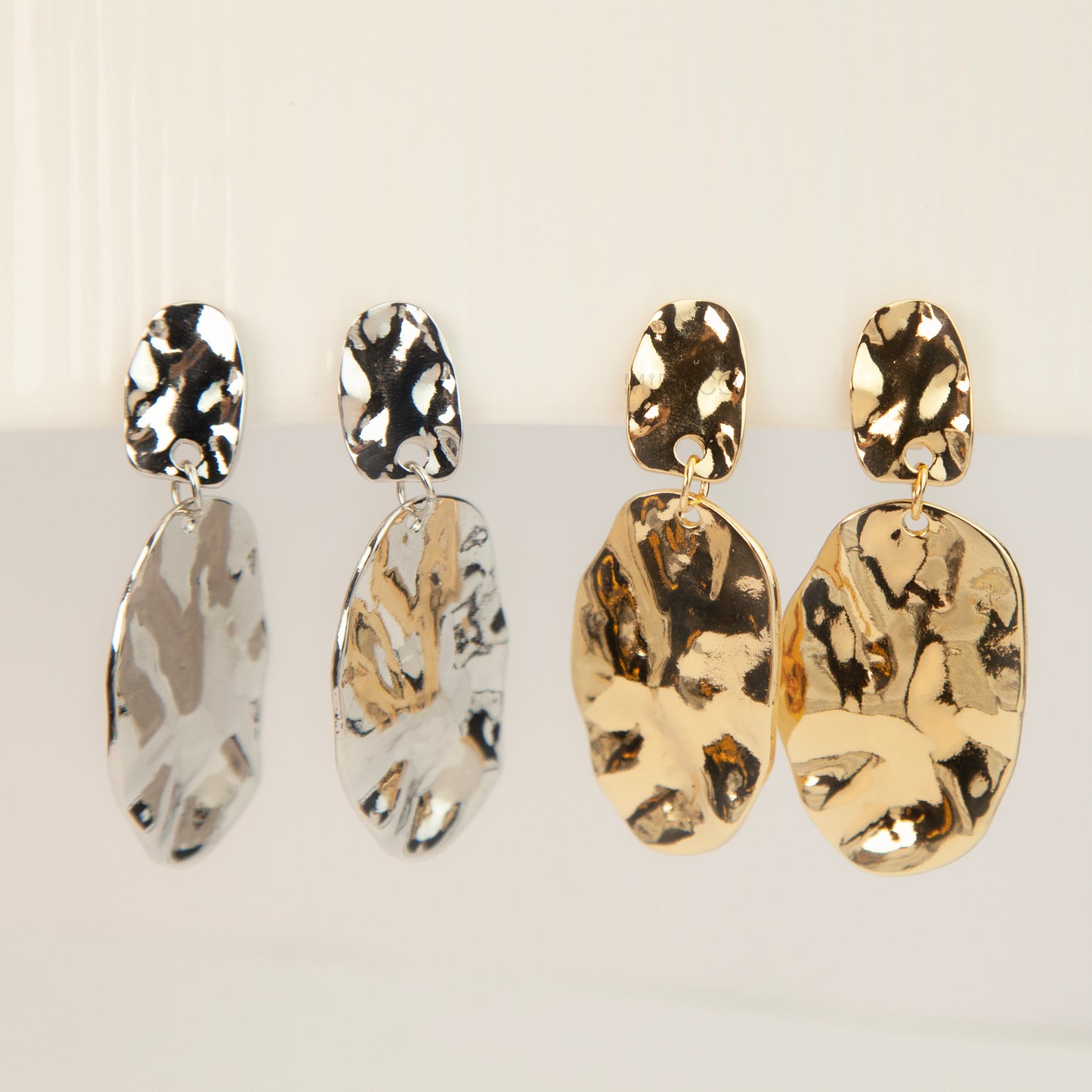 Gold and silver non-pierced statement clip-on earrings with mini clip backs, featuring hammered textured oval metal drop discs.