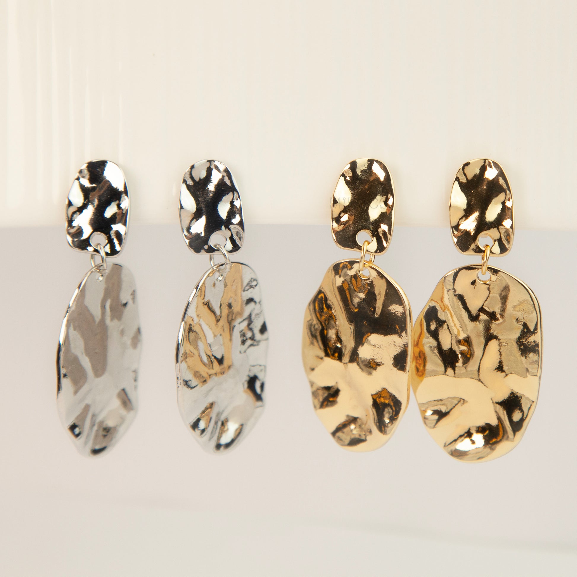 Gold and silver non-pierced statement clip-on earrings with mini clip backs, featuring hammered textured oval metal drop discs.