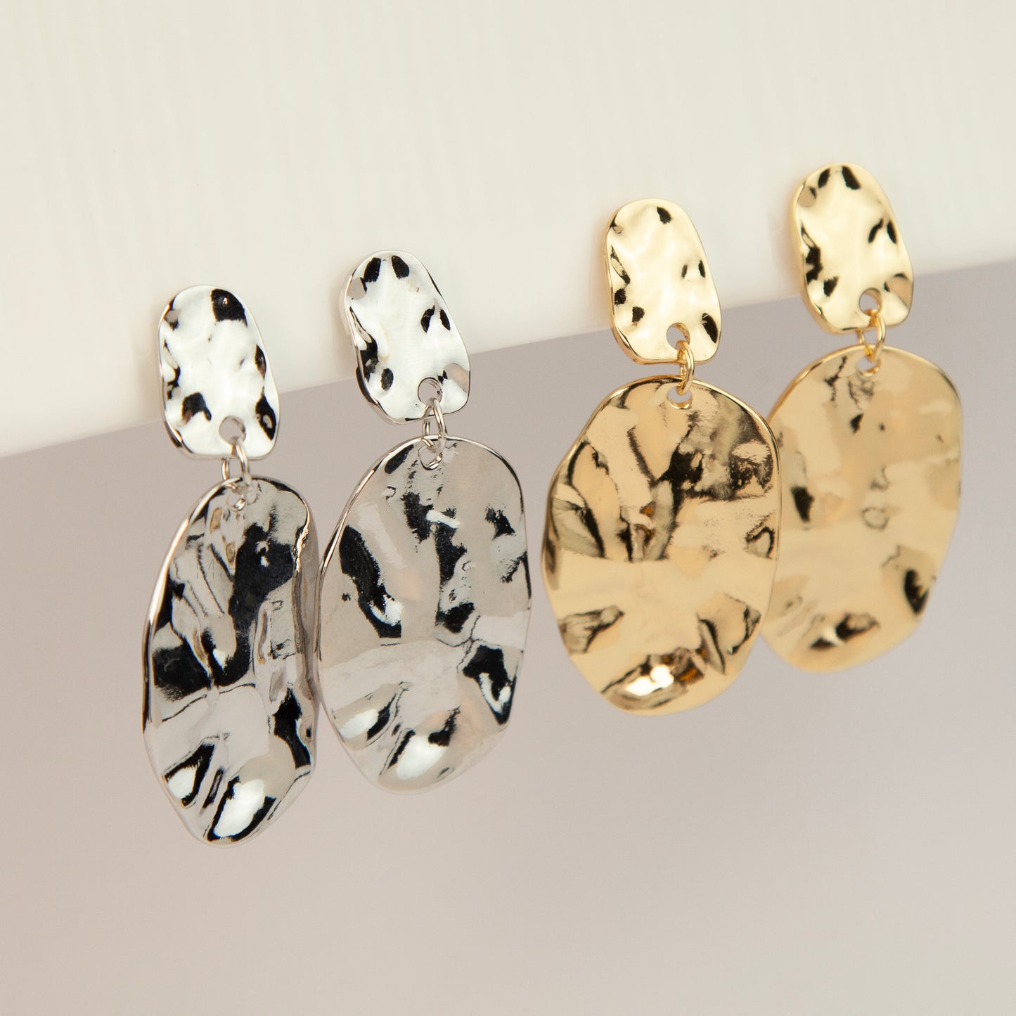 Gold and silver non-pierced statement clip-on earrings with mini clip backs, featuring hammered textured oval metal drop discs.