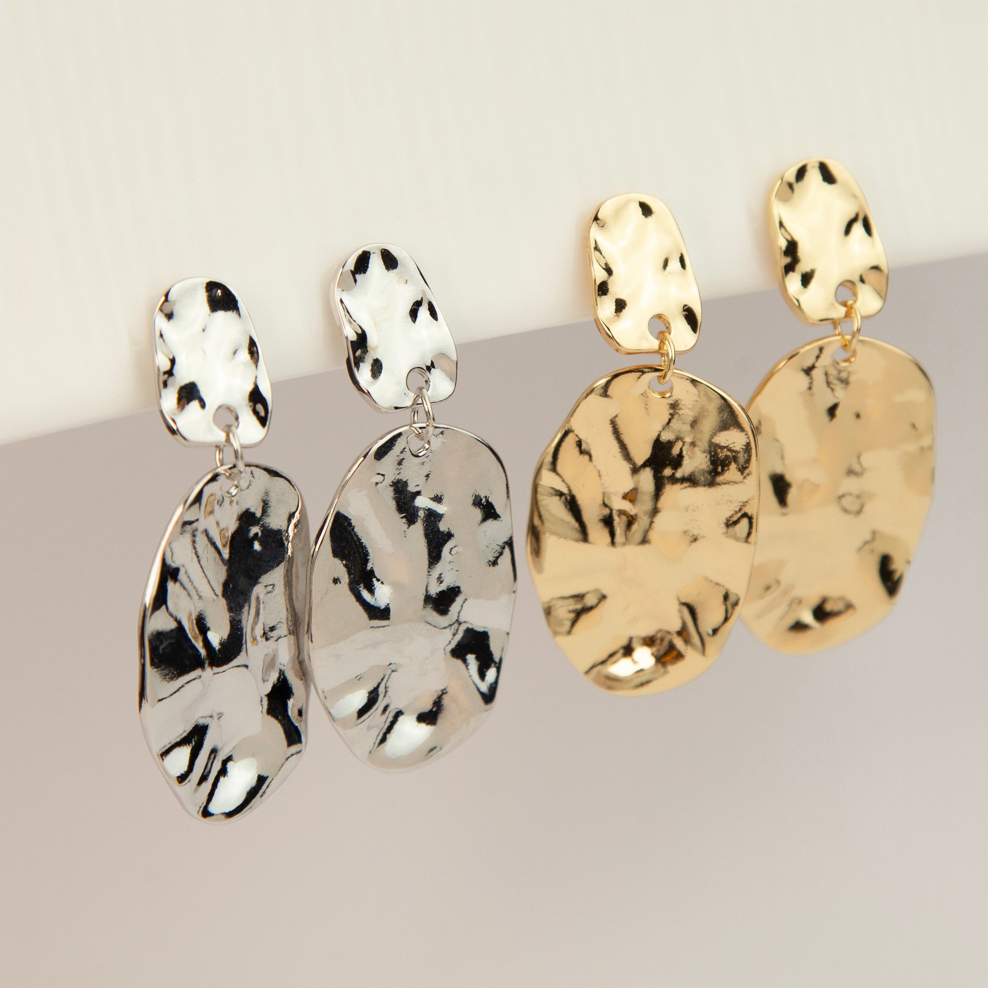 Gold and silver non-pierced statement clip-on earrings with mini clip backs, featuring hammered textured oval metal drop discs.