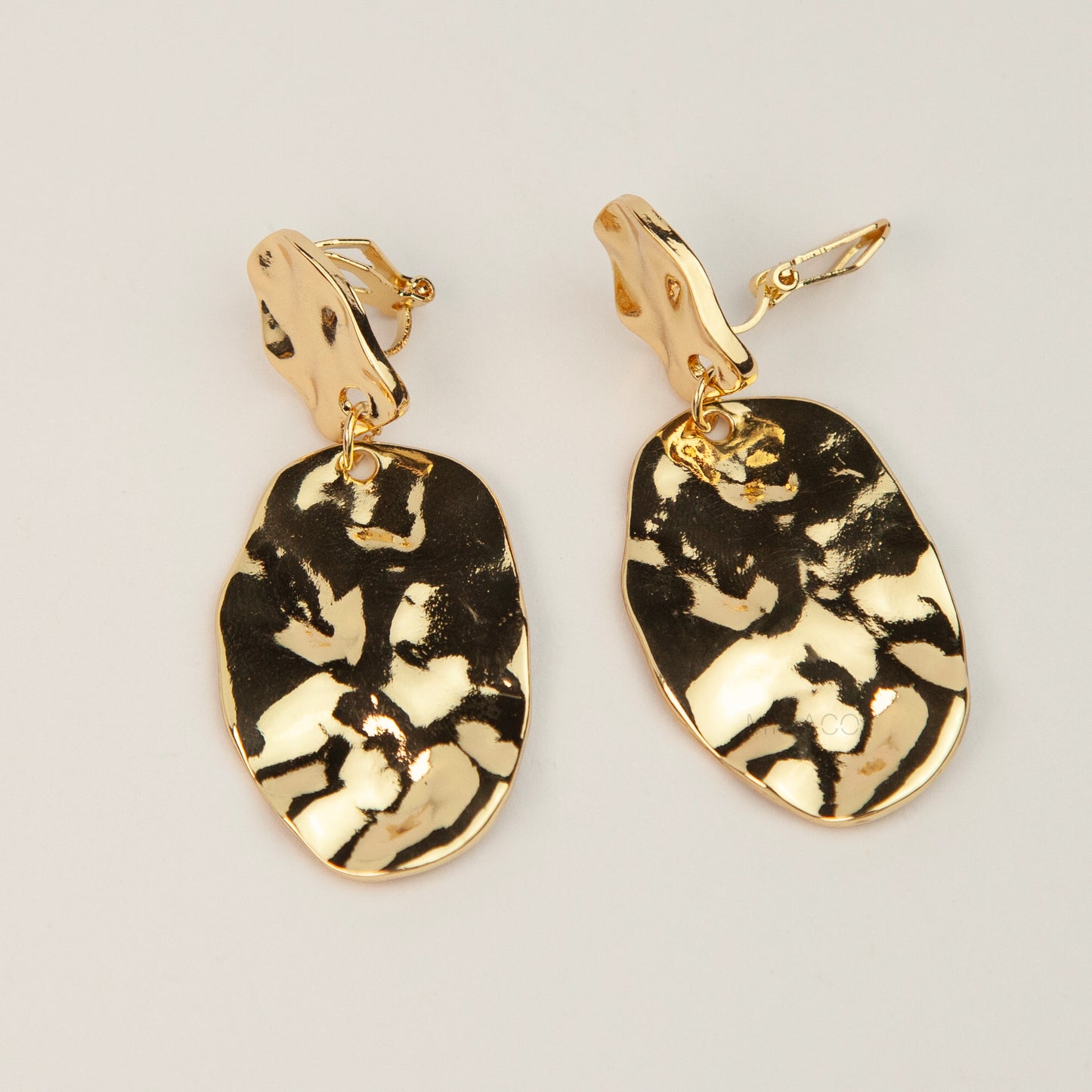 Gold and silver non-pierced statement clip-on earrings with mini clip backs, featuring hammered textured oval metal drop discs.